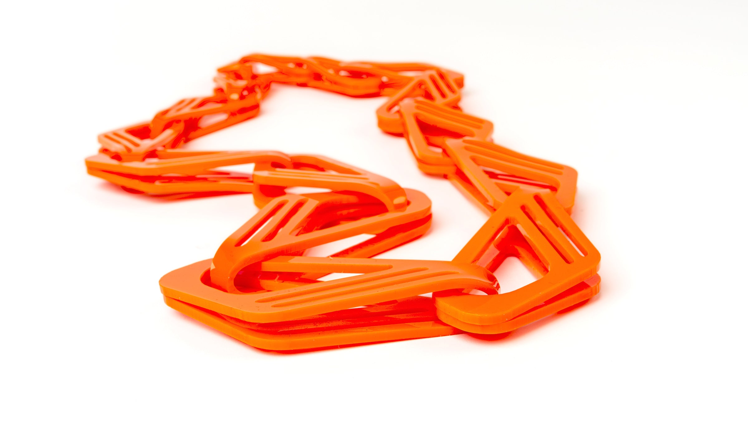 Bright orange chain made of acrylic sheet that has been cut and folded to create links.