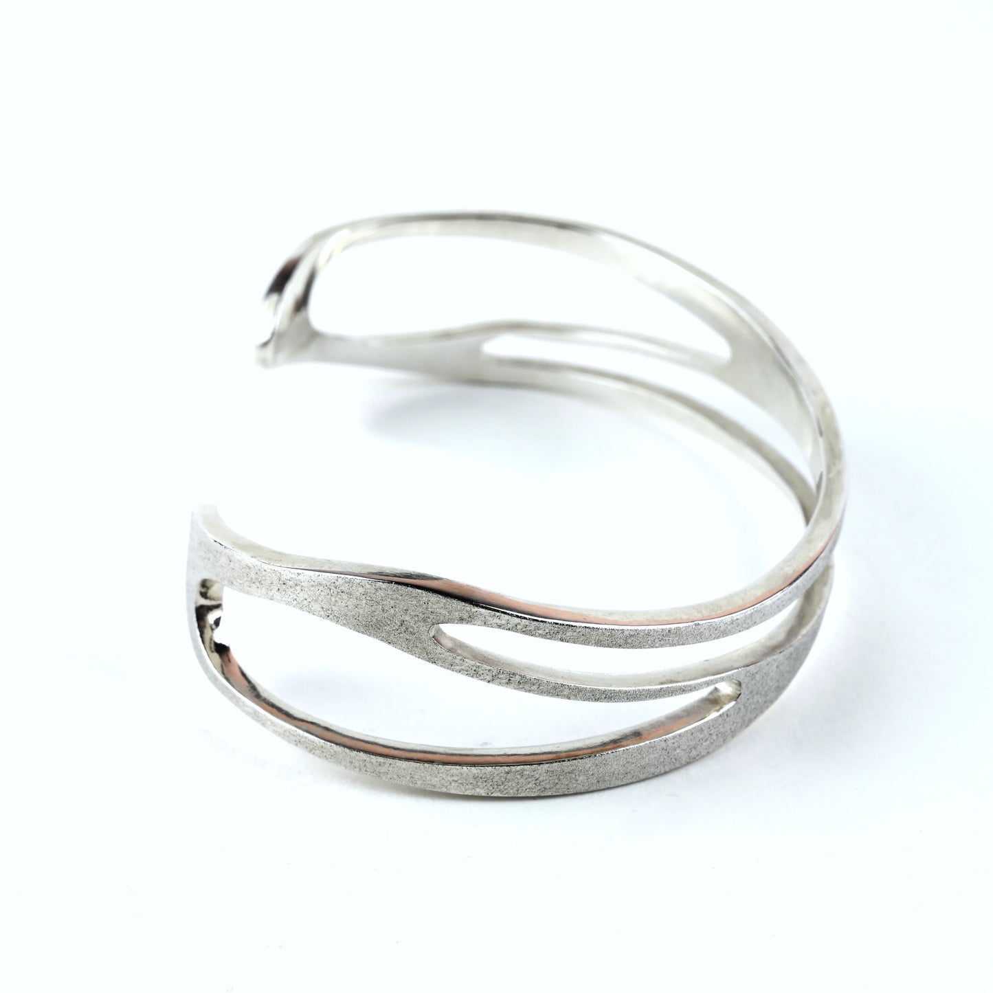 Mens silver cuff bracelet with organic curved shape and curved cut out areas on a white background