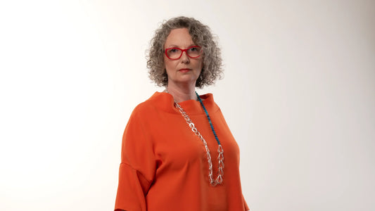 Victoria Hopkins stood in an orange top wearing a silver chain