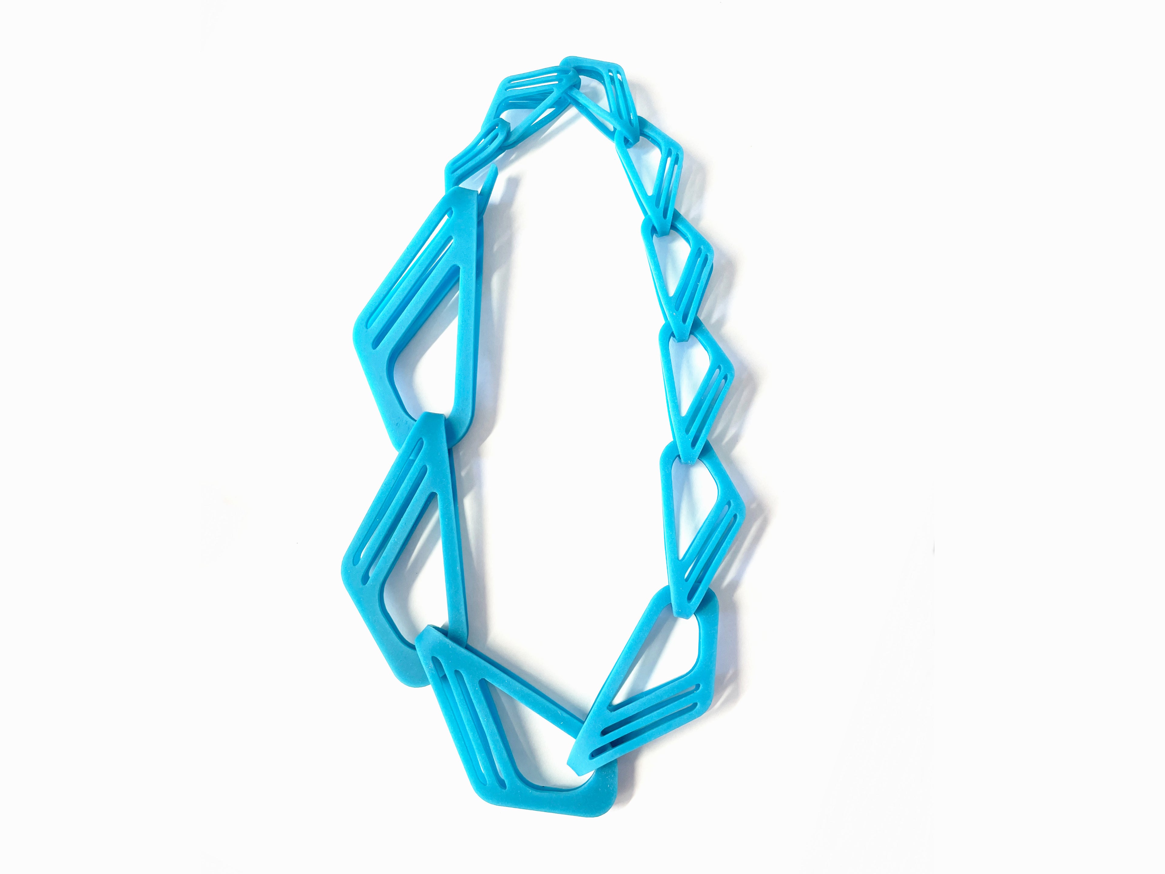 Blue acrylic chain made of joined links in different sizes from small to very large.  Each link has a curved cut out design.