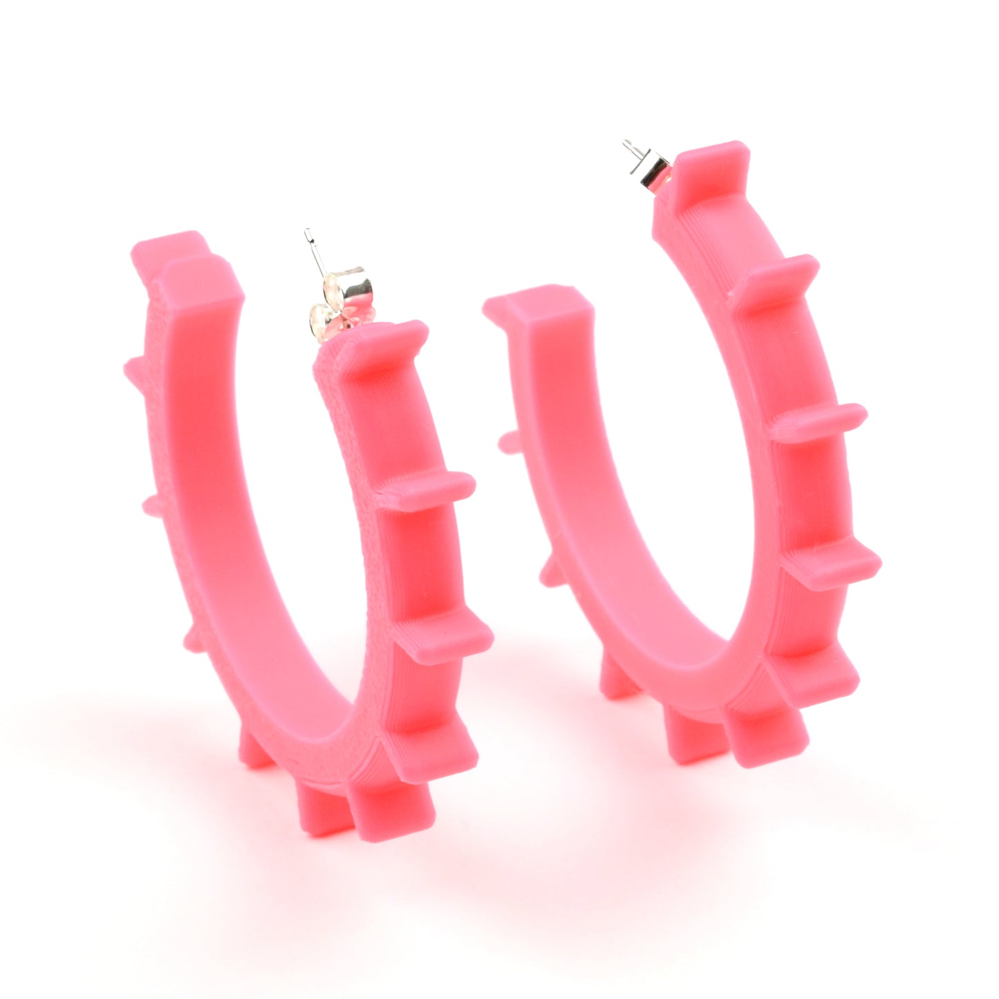 Flamingo pink plastic hoop earrings with silver ear posts and silver earring scroll backs.  They are medium sized with ridges running around the outside of the front edge of the hoops.
