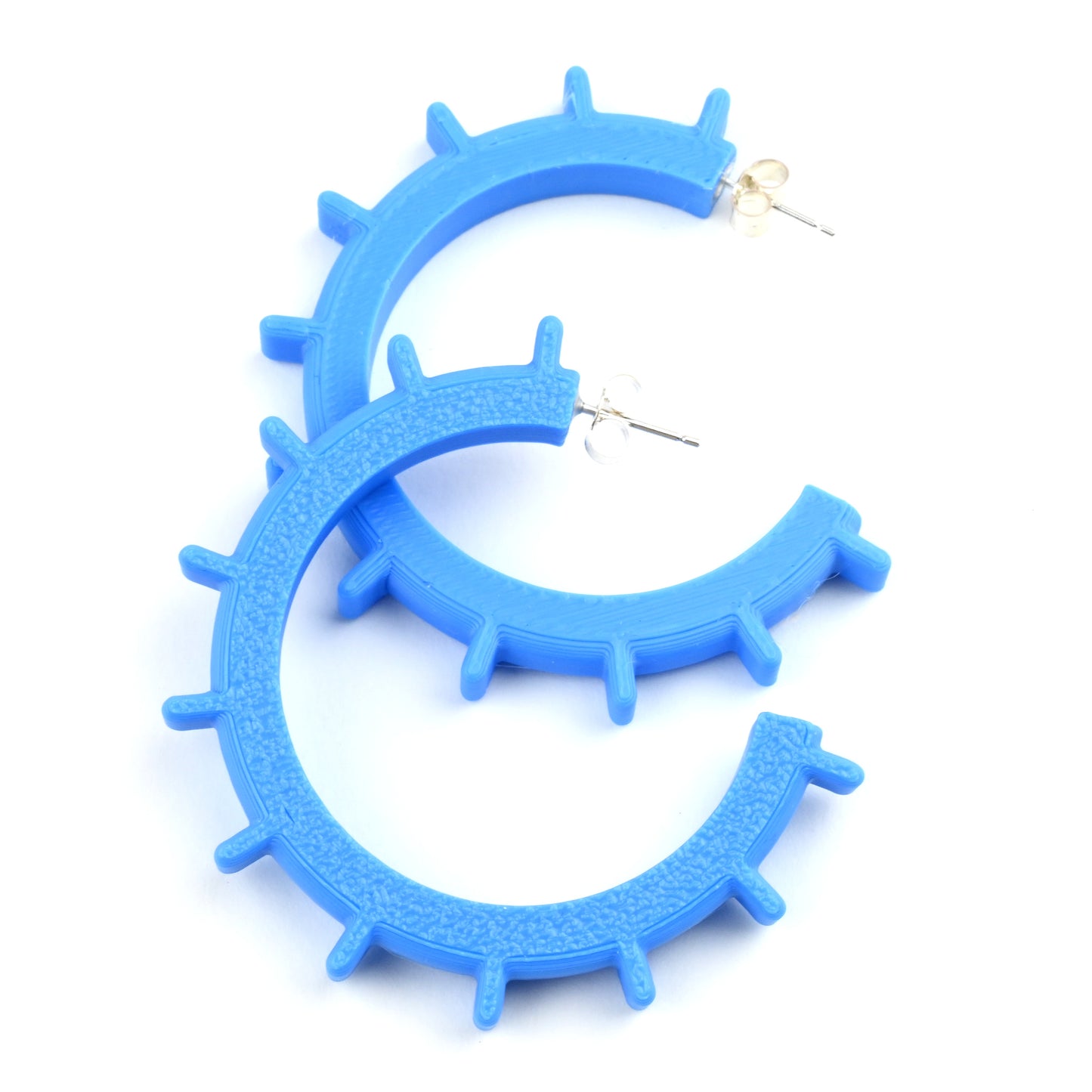 Cyan blue medium sized hoop earrings with silver ear posts and silver earring scroll backs.  The hoops have texture on one side and ridges sticking out around the outside of the hoop.