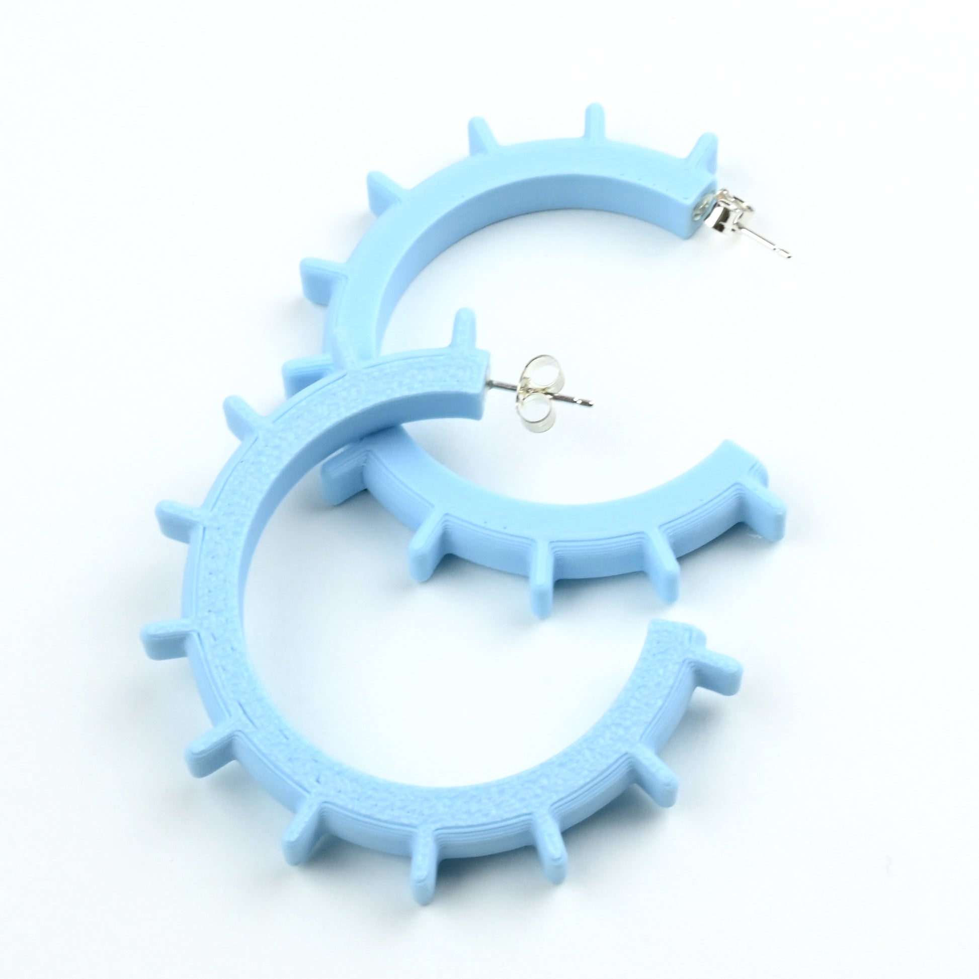 Medium sized pale blue plastic hoop earrings with silver ear posts and silver scrolls.  The earrings have ridges around the outside of the hoop.