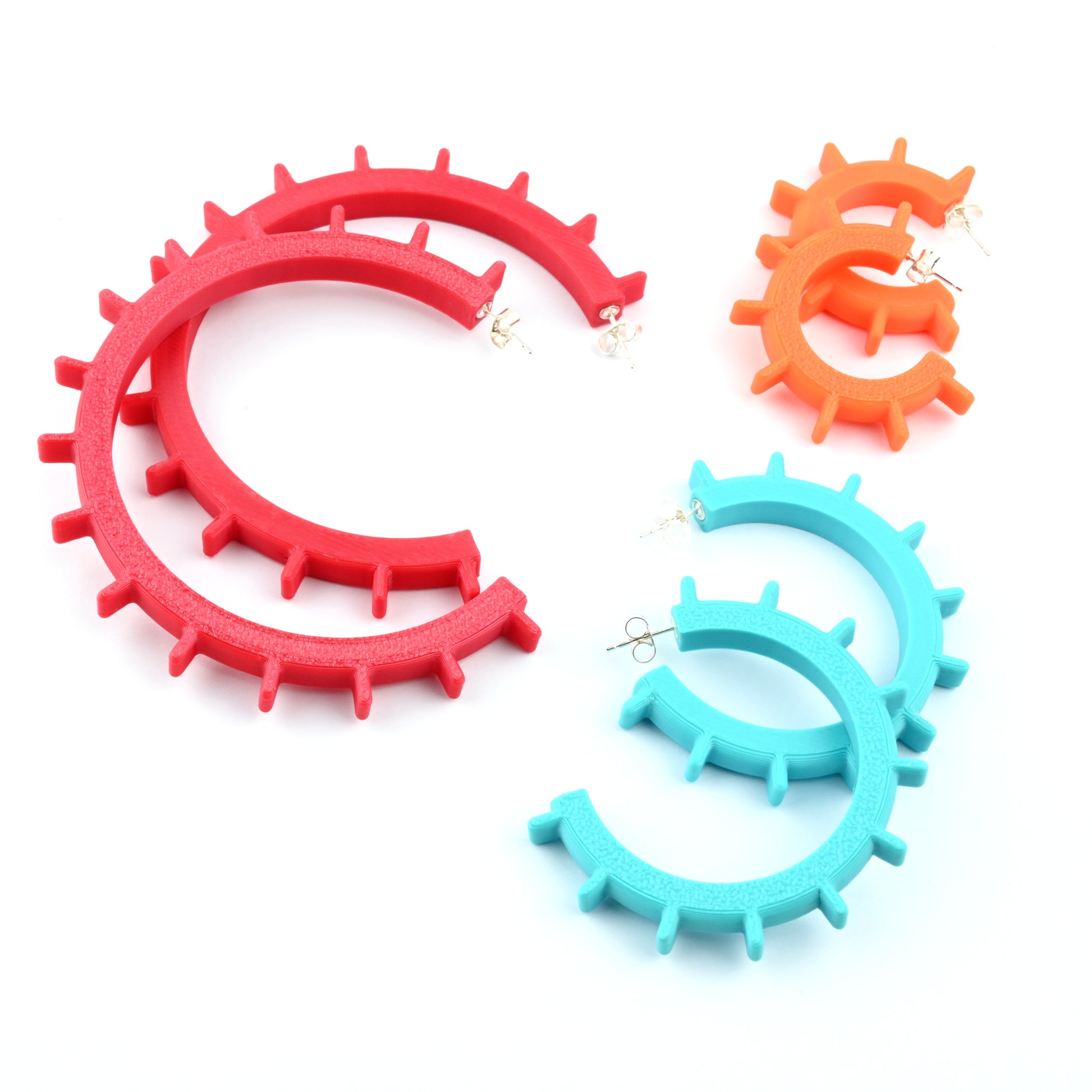 Three pairs of hoop earrings in different sizes. Earrings have an open circular shape with ridge design and silver ear posts.