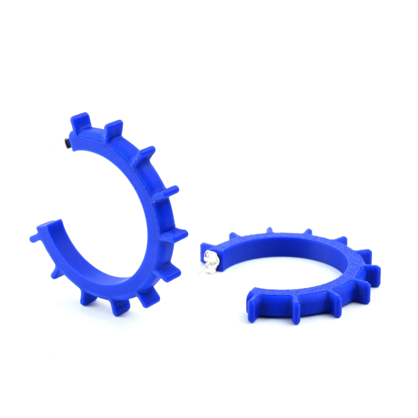 Pair of large blue cog shaped hoop earings with silver ear posts on a white background