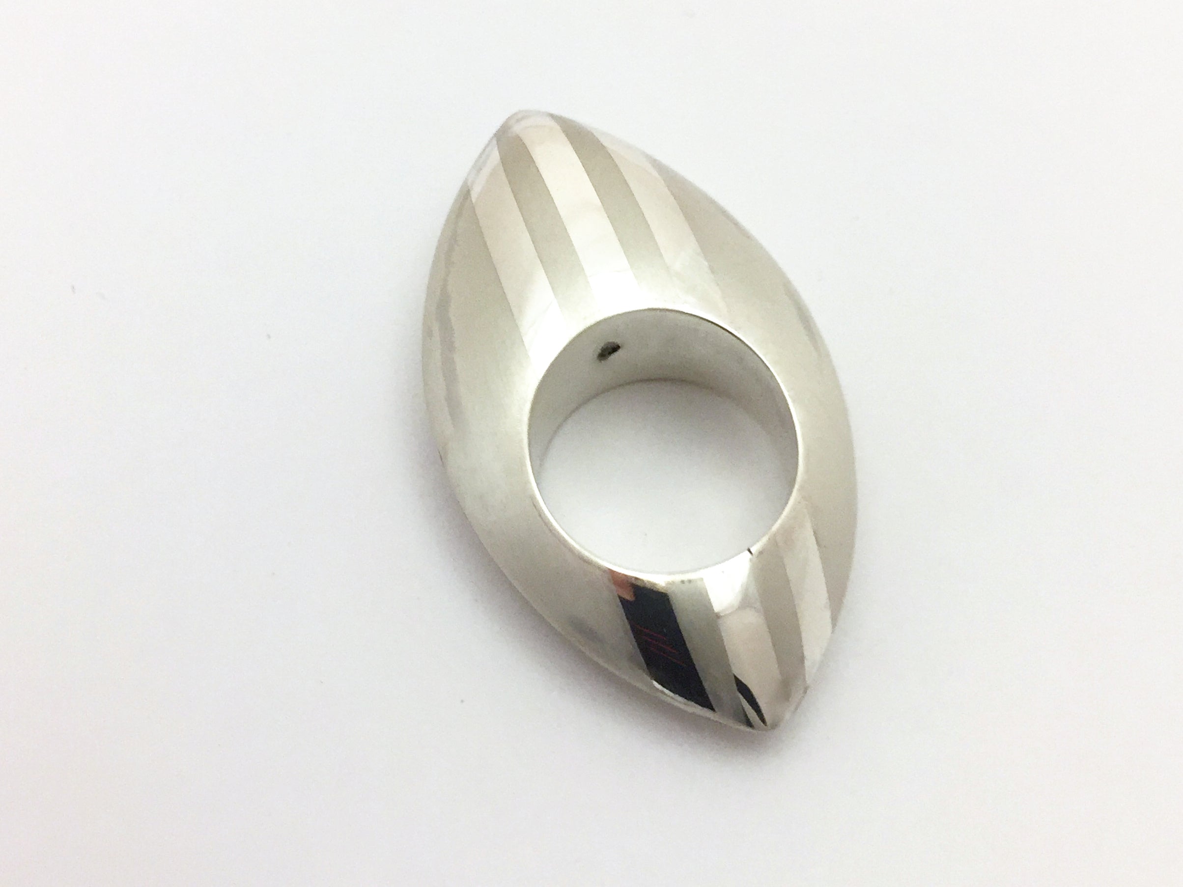 Oval shaped large silver ring with points at top and bottom.  The shape is domed.  It has a matt texture and three polished lines running down the centre of the ring from to bottom.