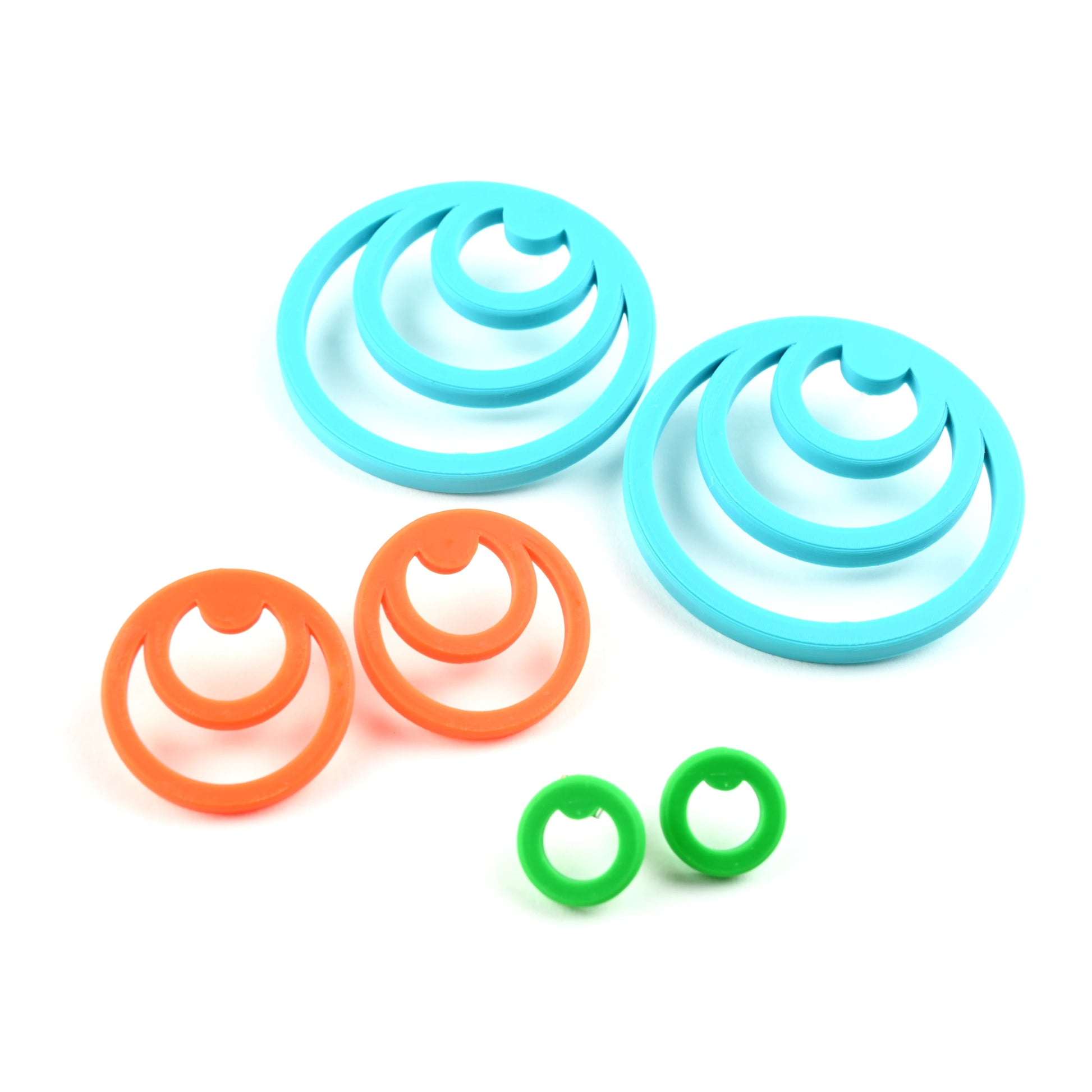 Three pairs of colorful circular earrings in orange, green and turquoise white background