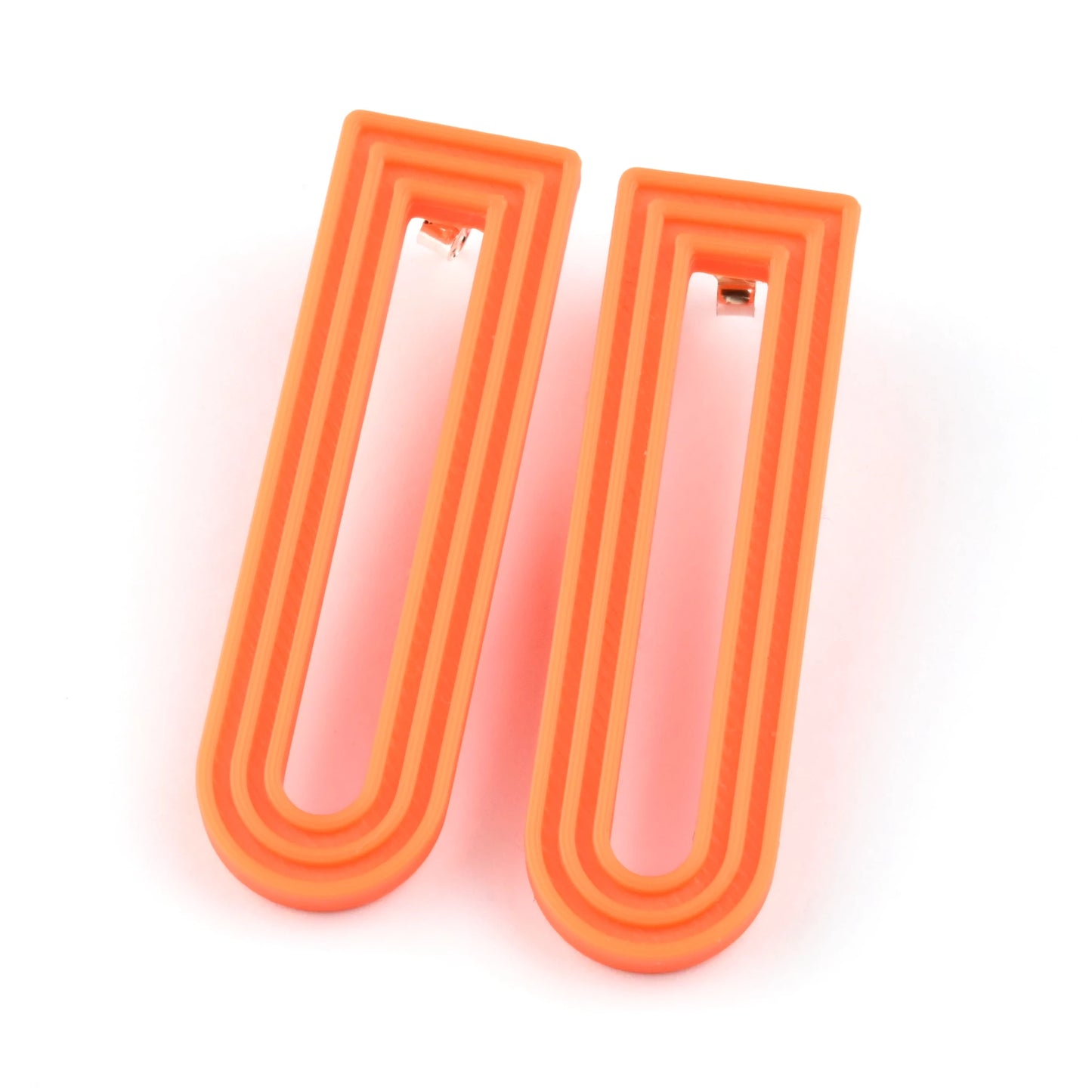 Orange U-shaped drop earrings with raised linear design on a white background