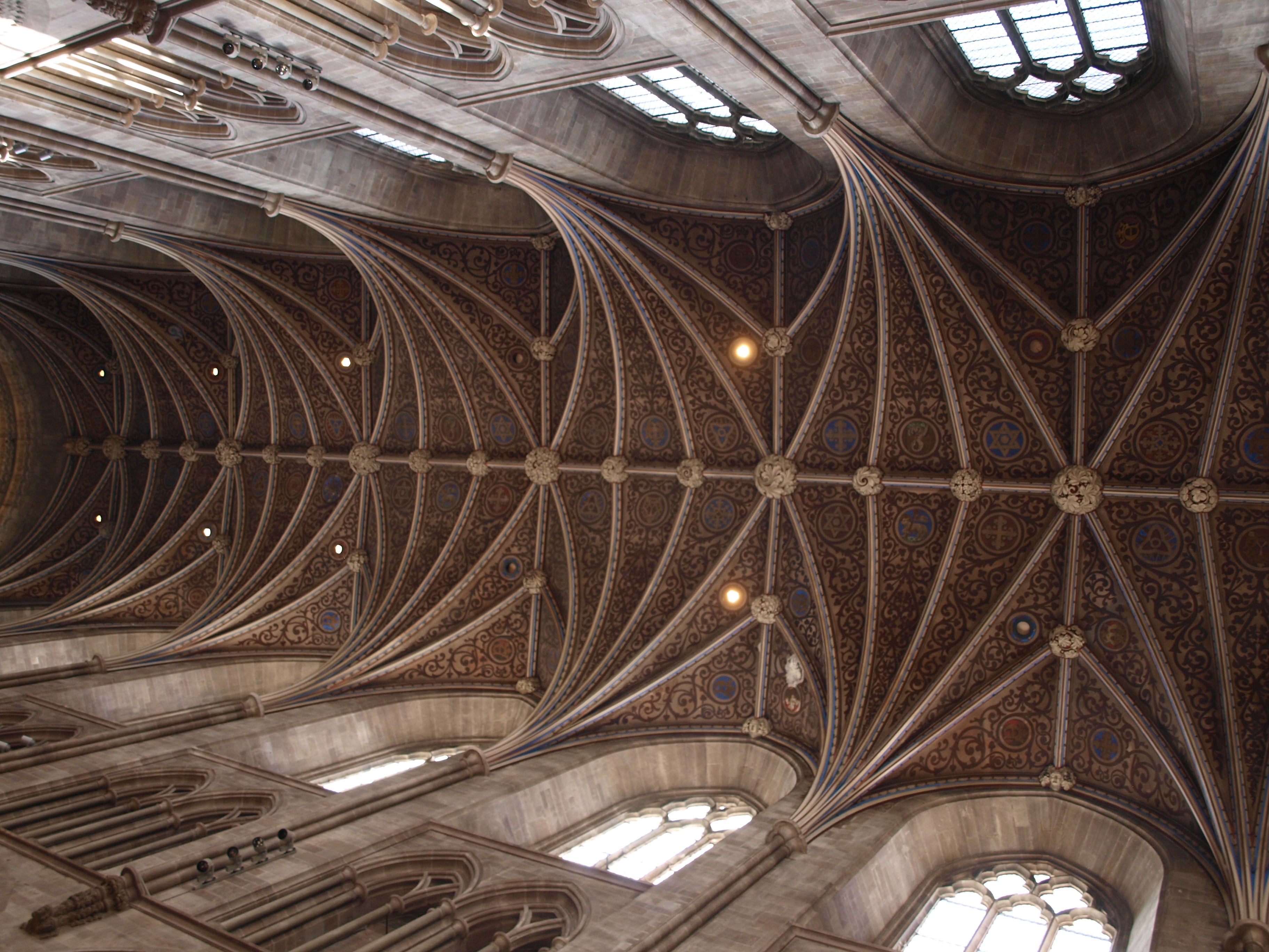Stone arches across Hereford Cathedral ceiling.  The ceiling is painted in red and blue patterns.