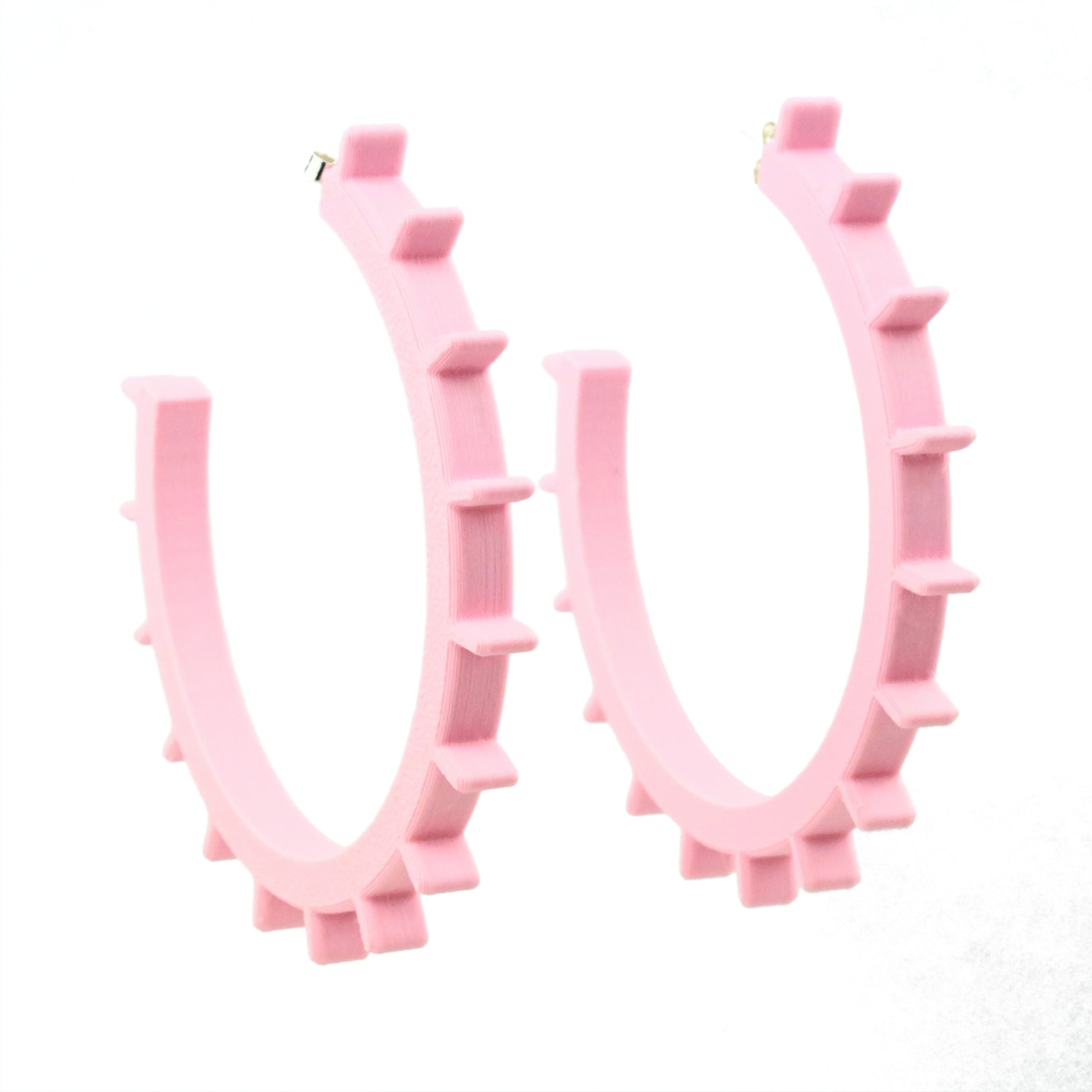 Huge pale pink plastic hoop earrings with ridges along the front edge of the earrings.  