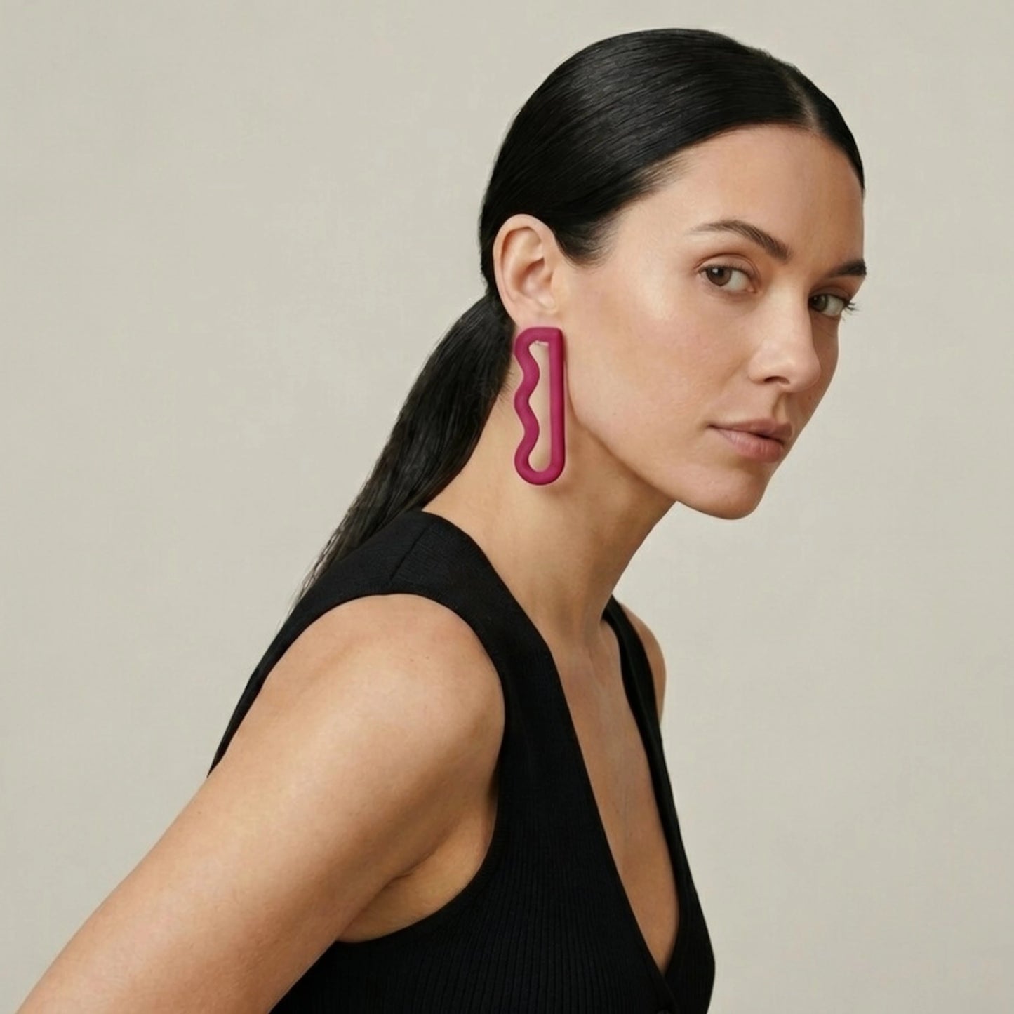 3D printed long drop plum earrings with a wavy linear design worn by a model in a black dress