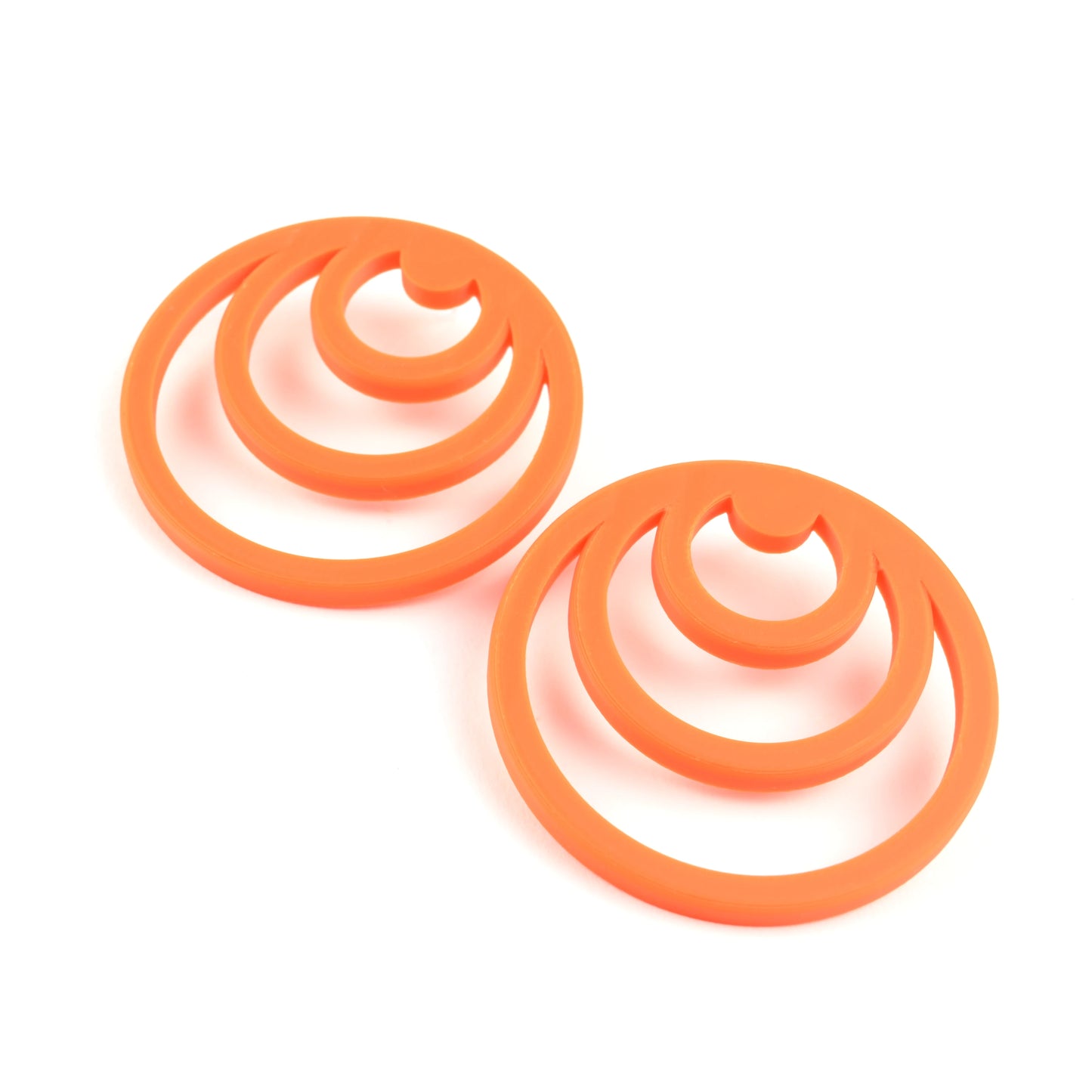 Pair of orange earrings with three orange cirlces inside each other on a white background