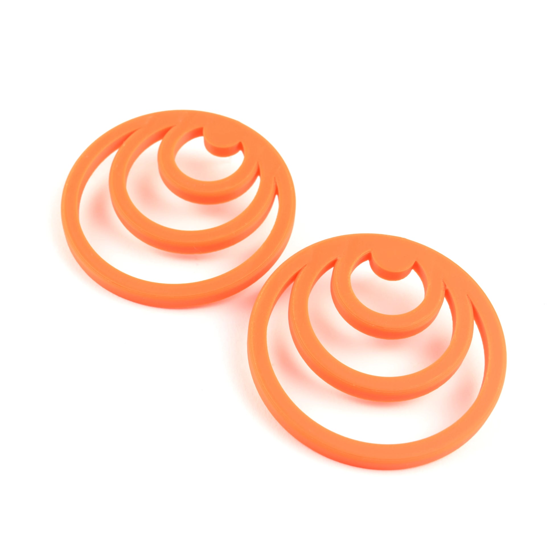 Pair of orange earrings with three orange cirlces inside each other on a white background