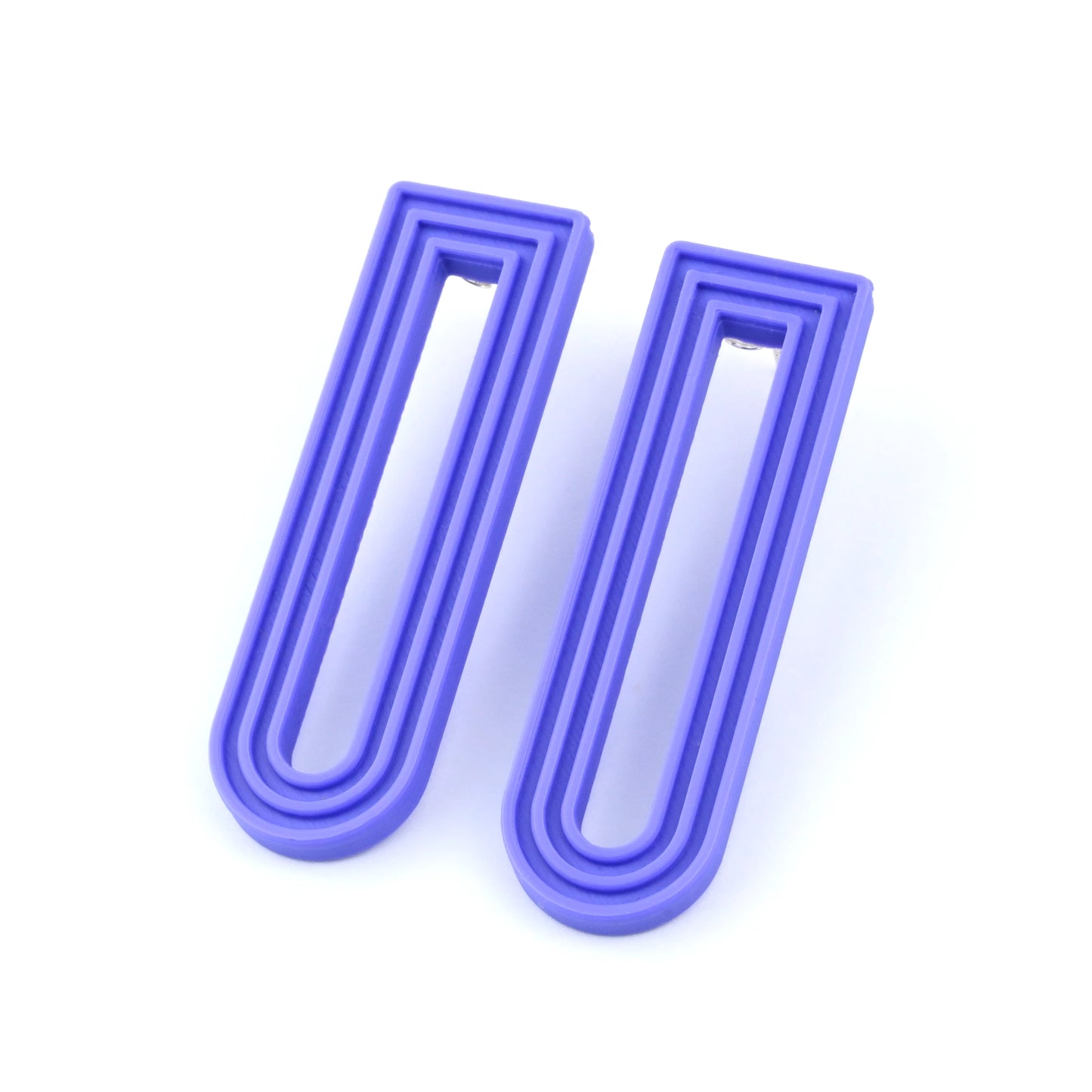 Pair of purple U-shaped drop earrings with raised linear design on a white background