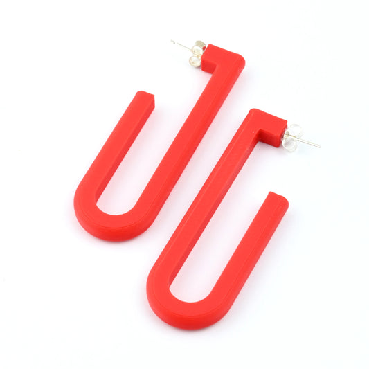 Red 'U' shaped hoop earrings on a white background
