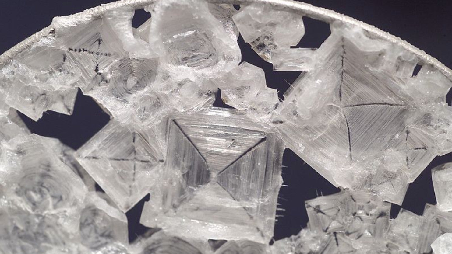 Salt viewed under a microscope showing pyramid shapes joined together in an adhoc way.