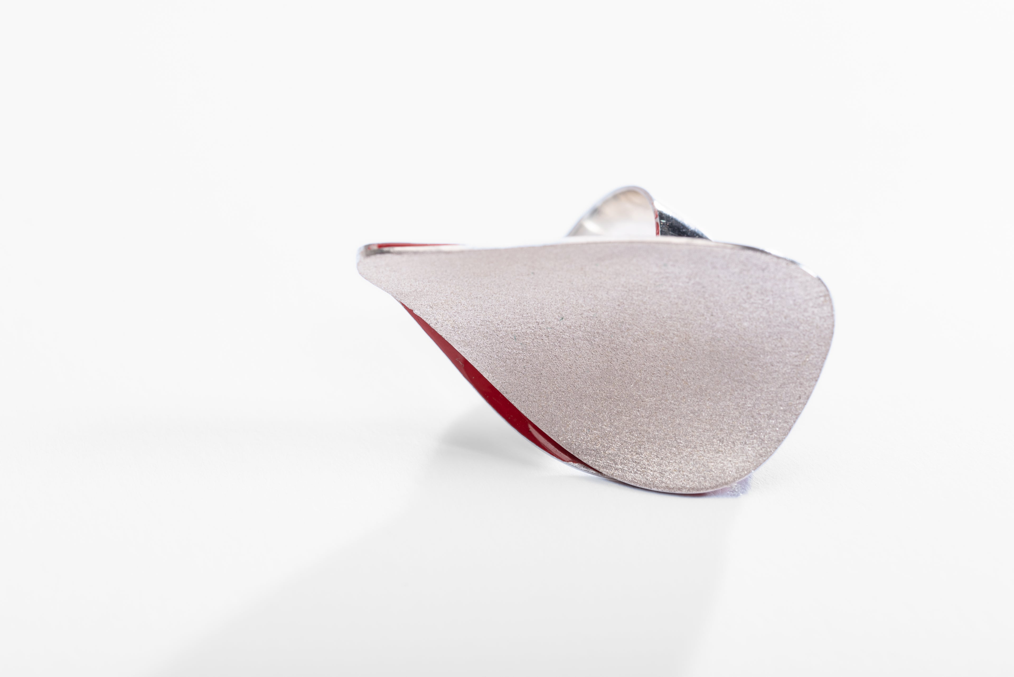Large silver cocktail ring with curved glittering teardrop shape on a twisted silver ring band.  There is a little bit of red enamel visible form the inside of the ring.