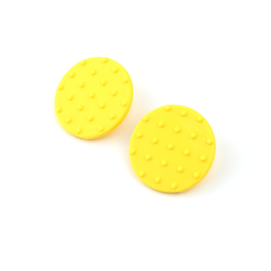 A pair of yellow round disk earrings with raised dot pattern on a white background
