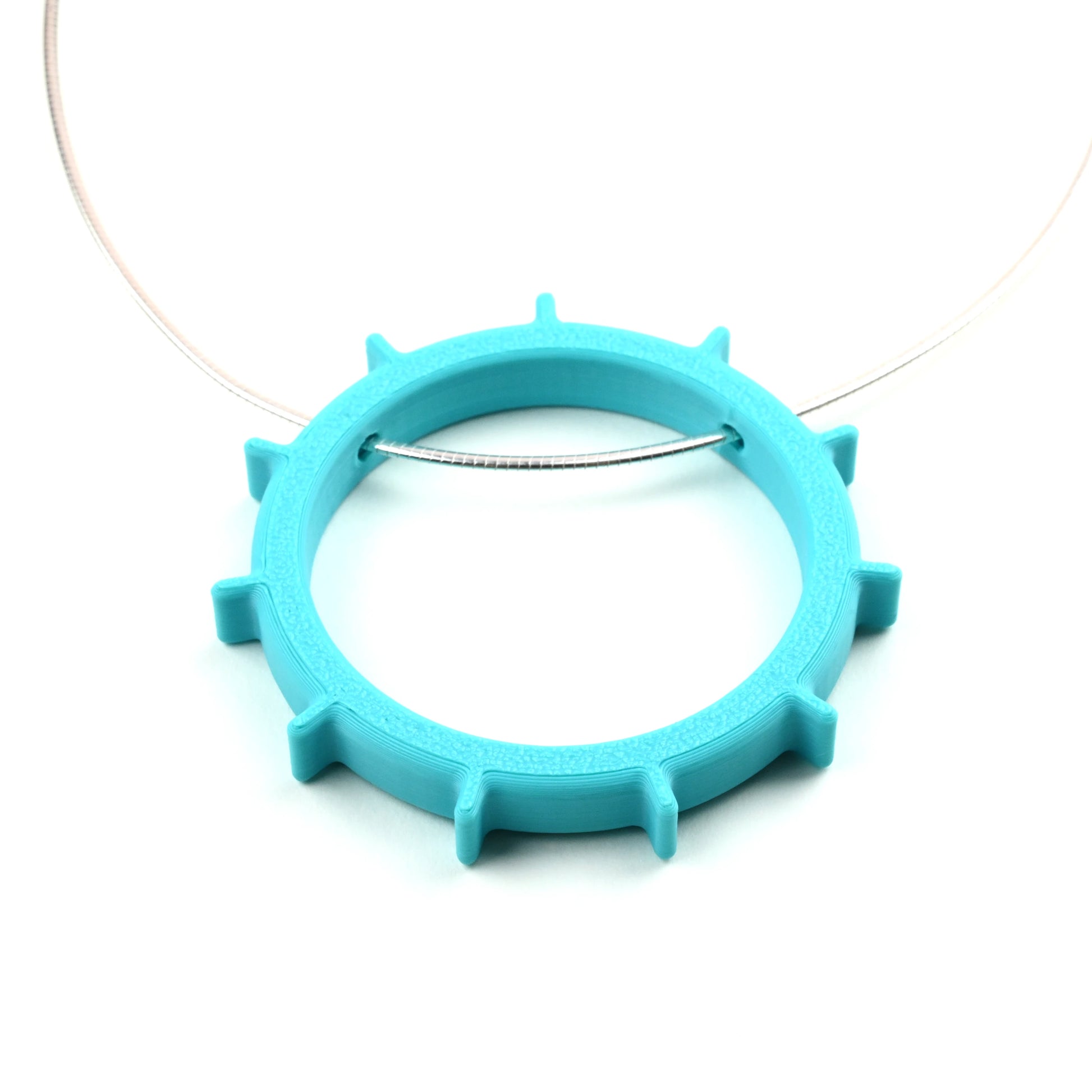 Turquoise necklace with a unique circular design on a silver cable necklet on a white background