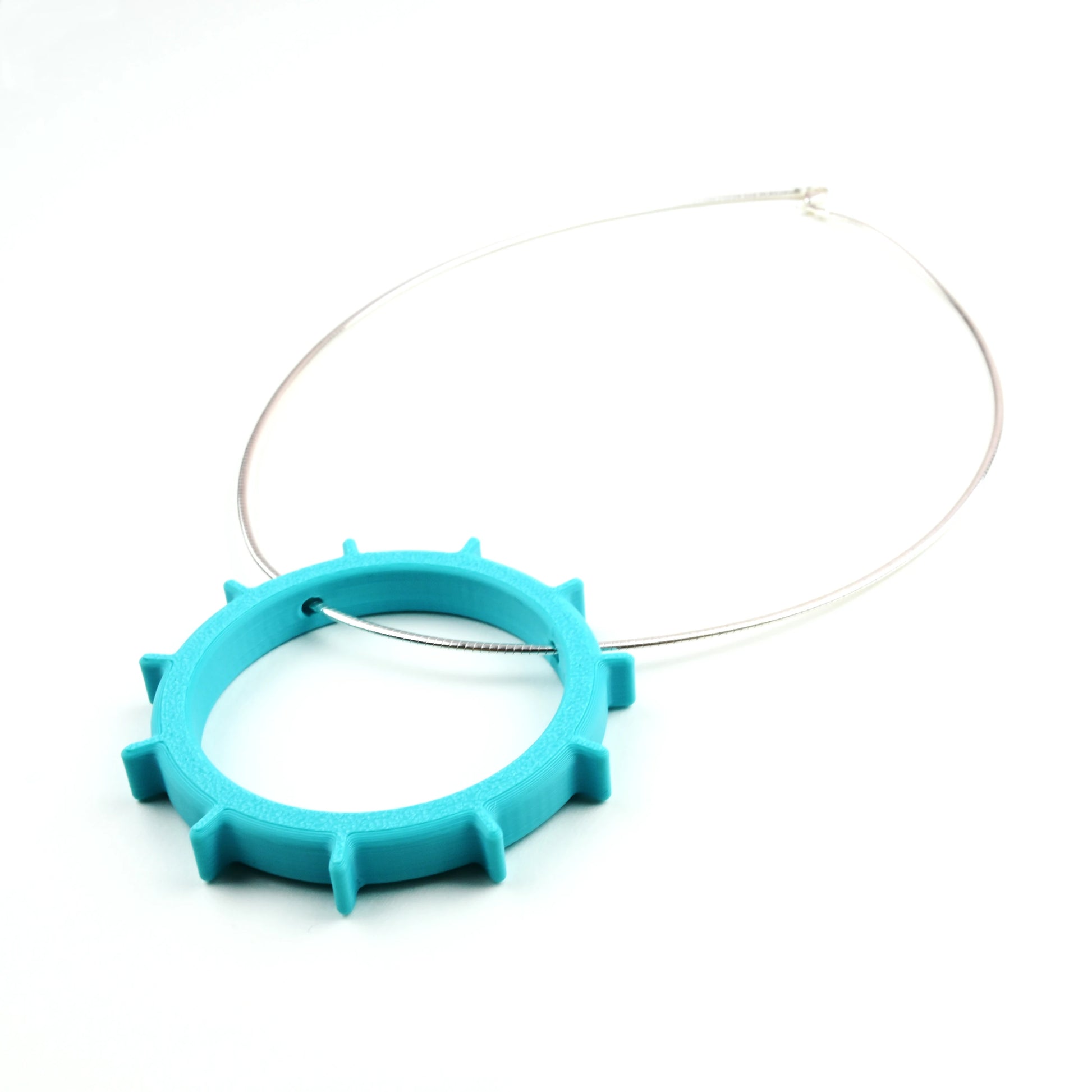 Turquoise necklace with a unique circular design on a silver cable necklet on a white background
