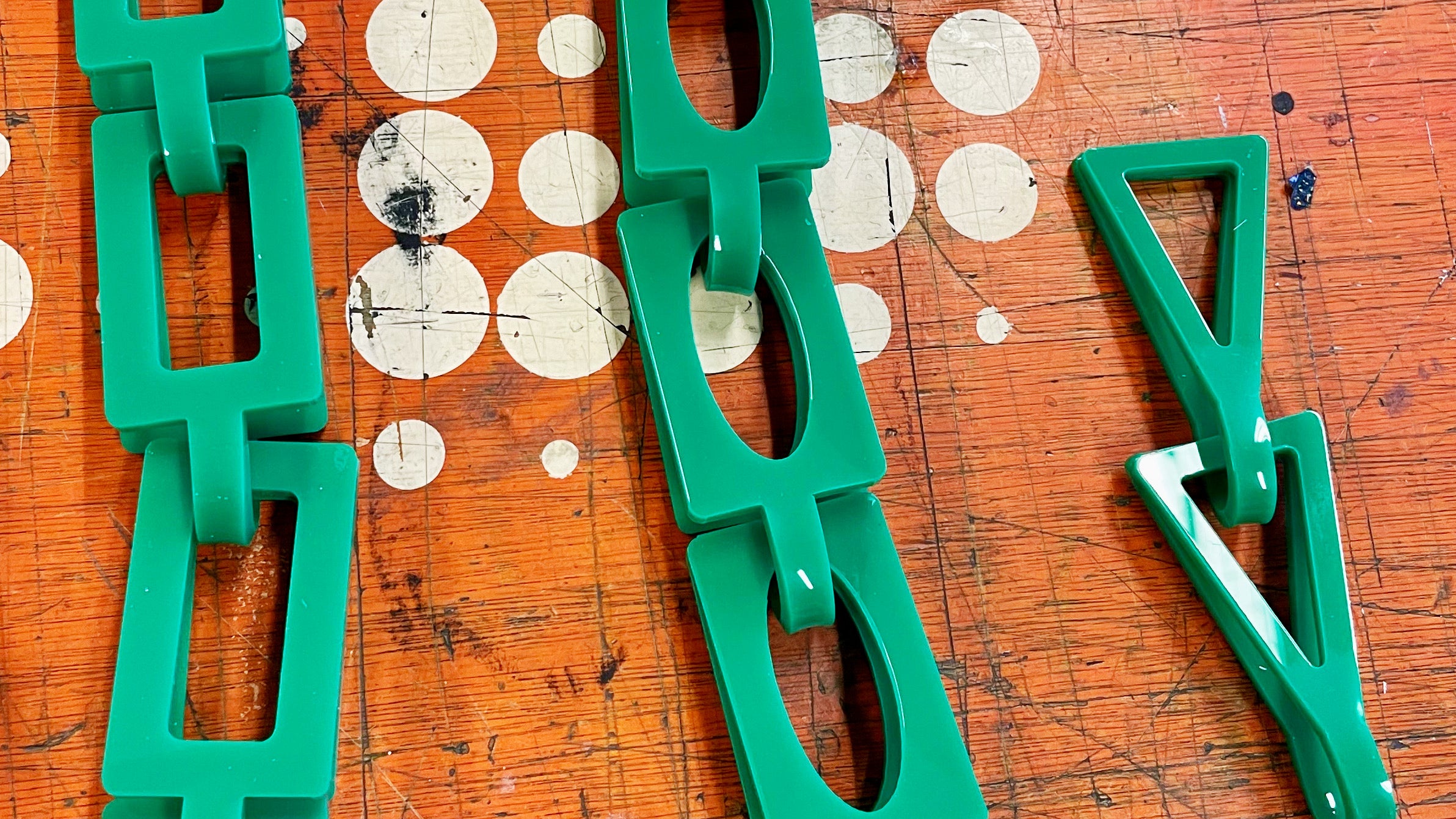 Green loop-in-loop chains in various shapes including triangular and rectangular.  The chain is made using green acrylic sheet and the links are very large.