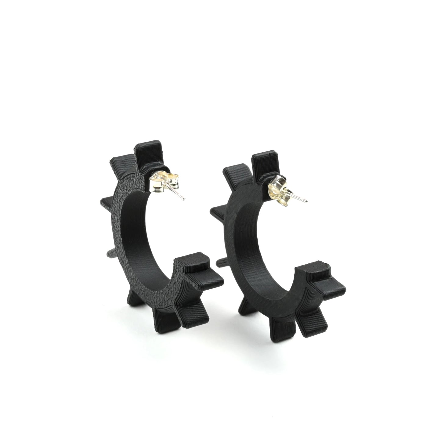 Small black spiked hoop earrings on a white background with silver ear posts and earring backs. 