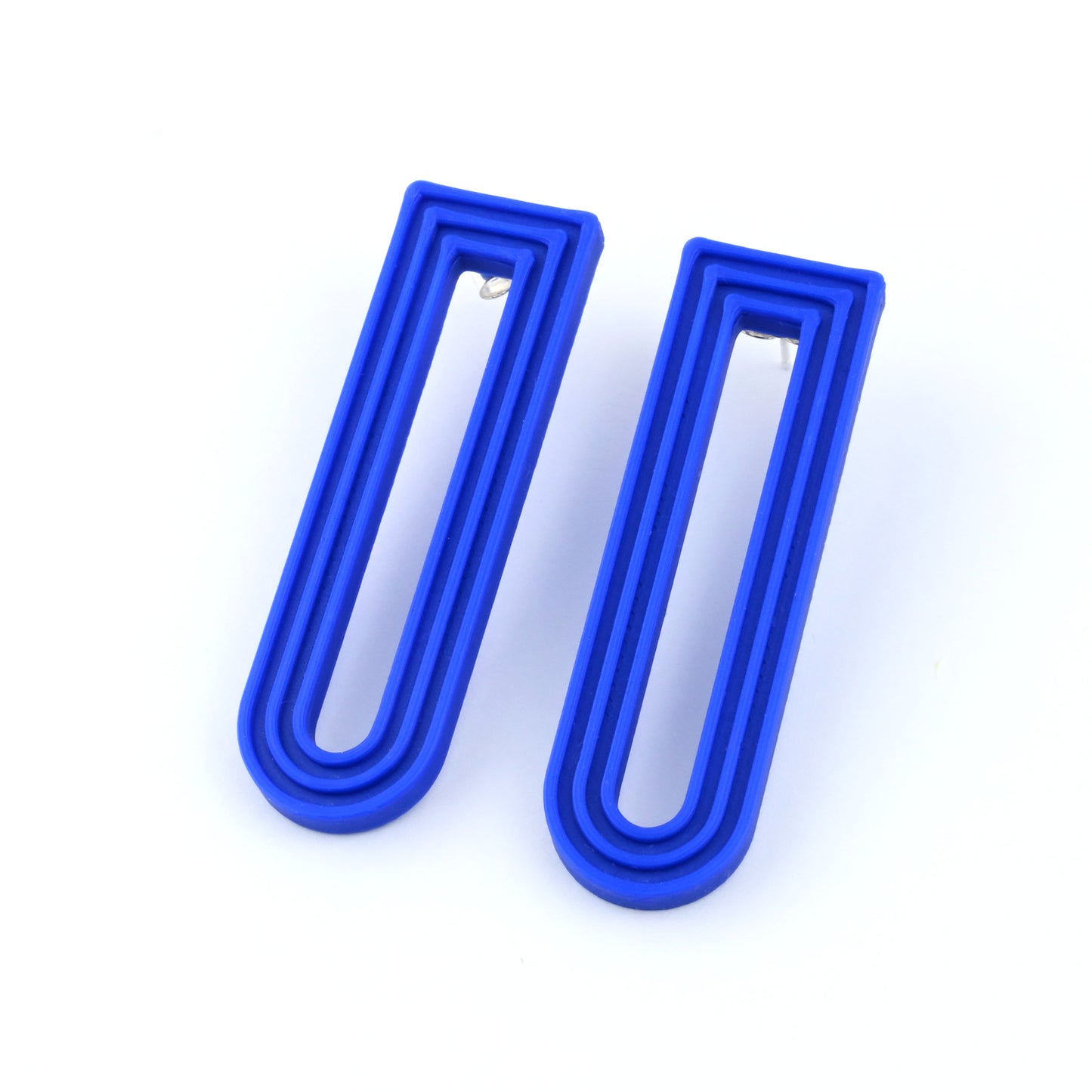 Blue U-shaped drop earrings with raised linear design on a white background
