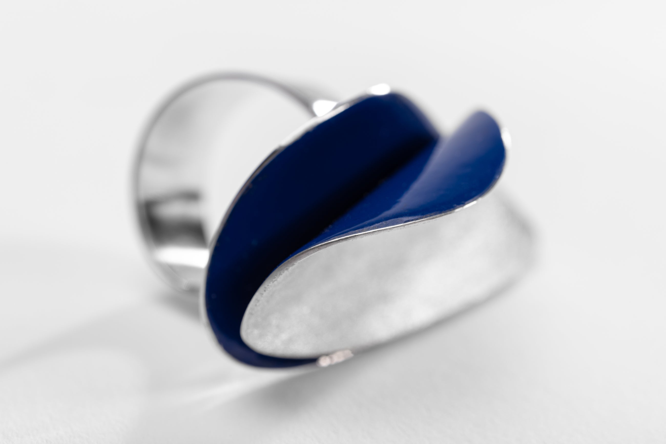 Bold silver ring with curved shape and blue enamel interior.