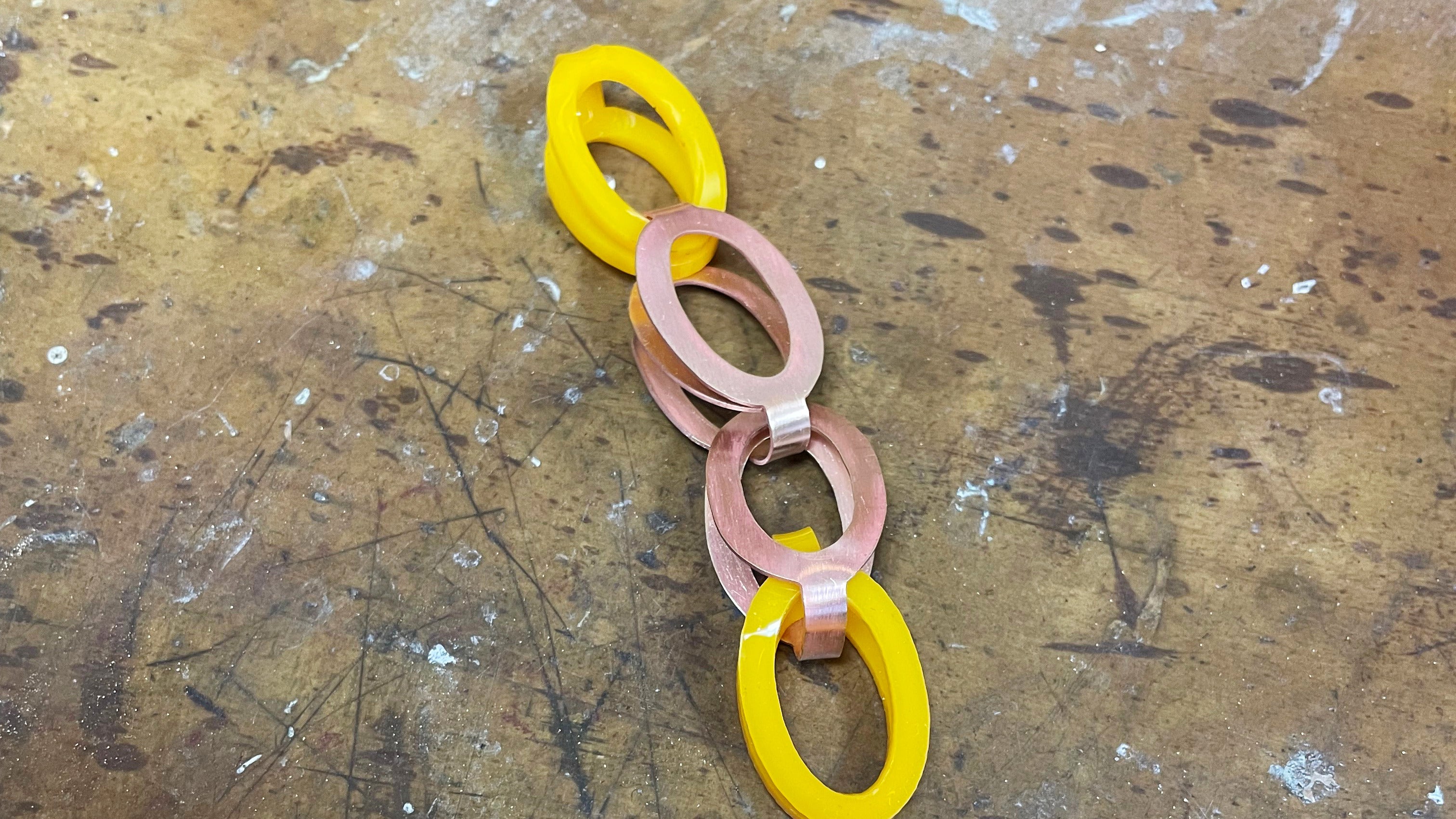 Yellow loop-in-loop chain with oval shaped links made using acrylic sheet, with a copper coloured clasp matching the link style and size. 
