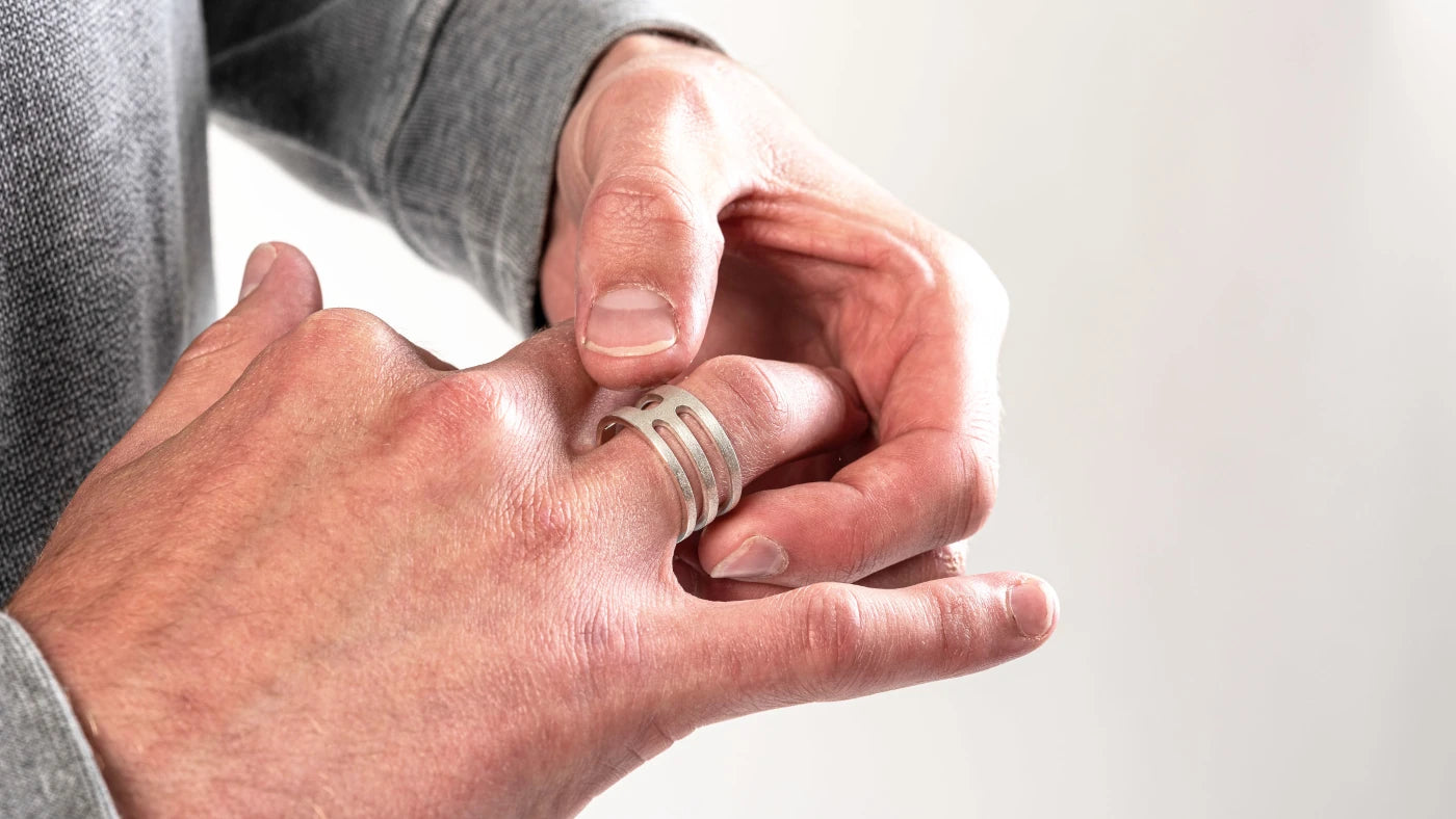 Mans hand wearing a geometric silver ring.