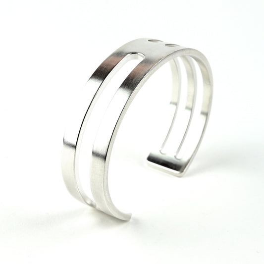 Silver cuff bracelet with geometric cut outs on a white background