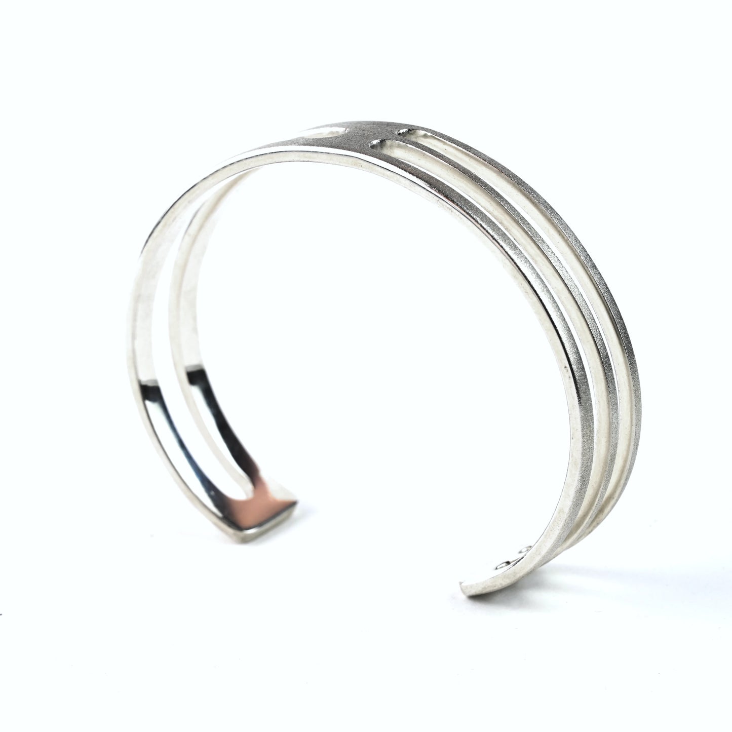 Mens silver cuff bracelet with geometric cut outs on a white background