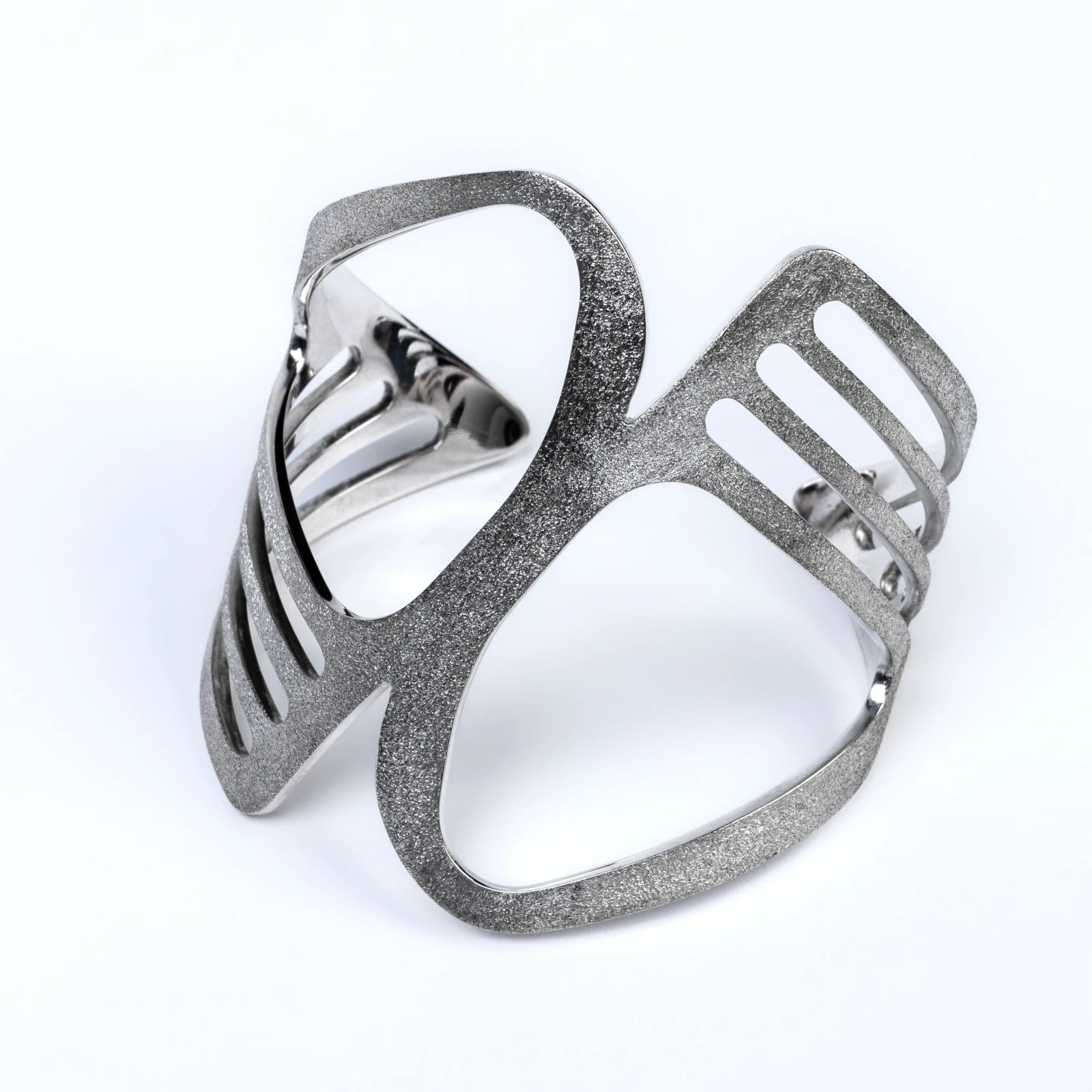 Wide silver sttement cuff with a unique cut out design and frosted texture on a white background