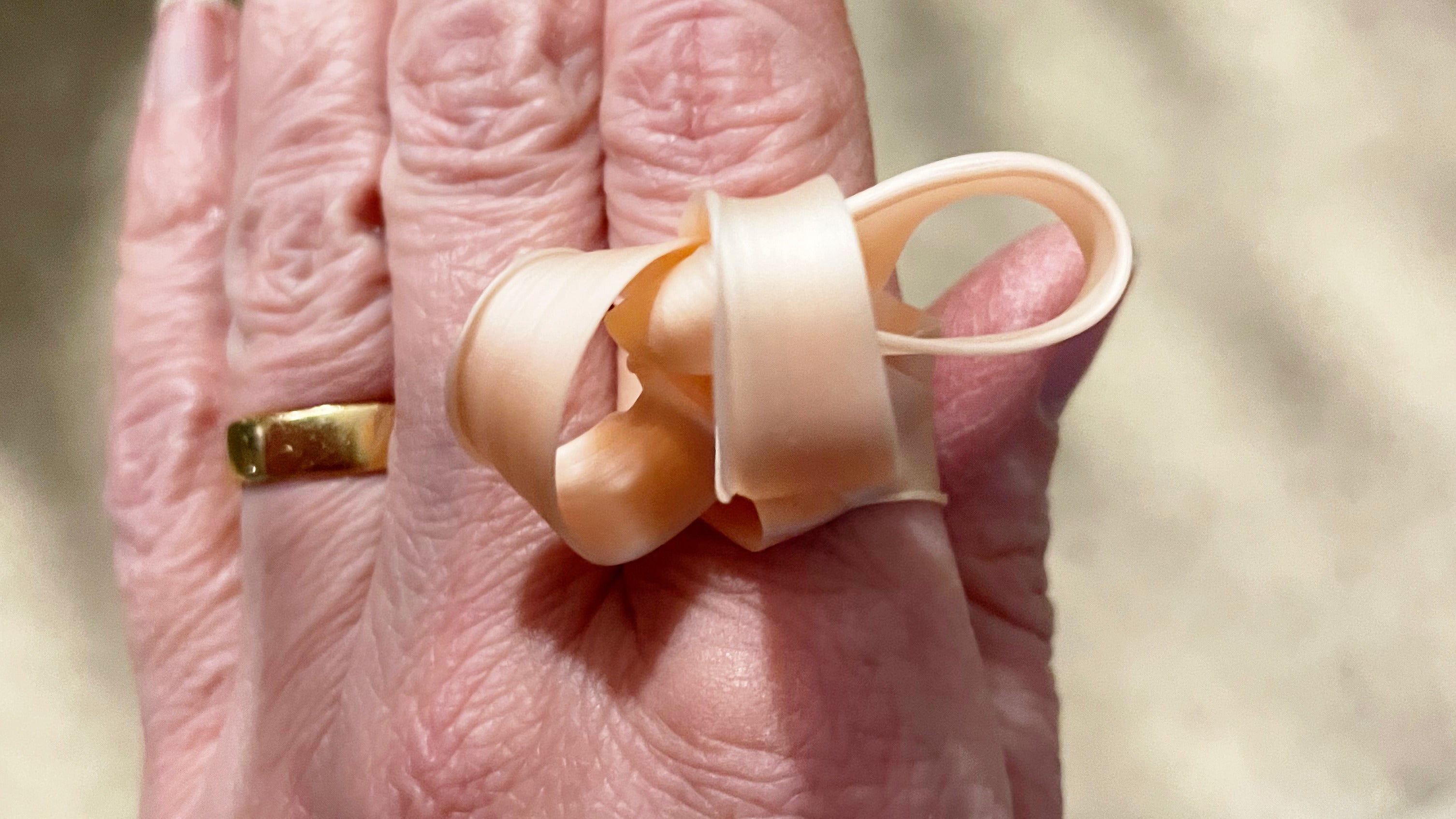 Strips of wax looped around above a simple ring band being worn on a hand.