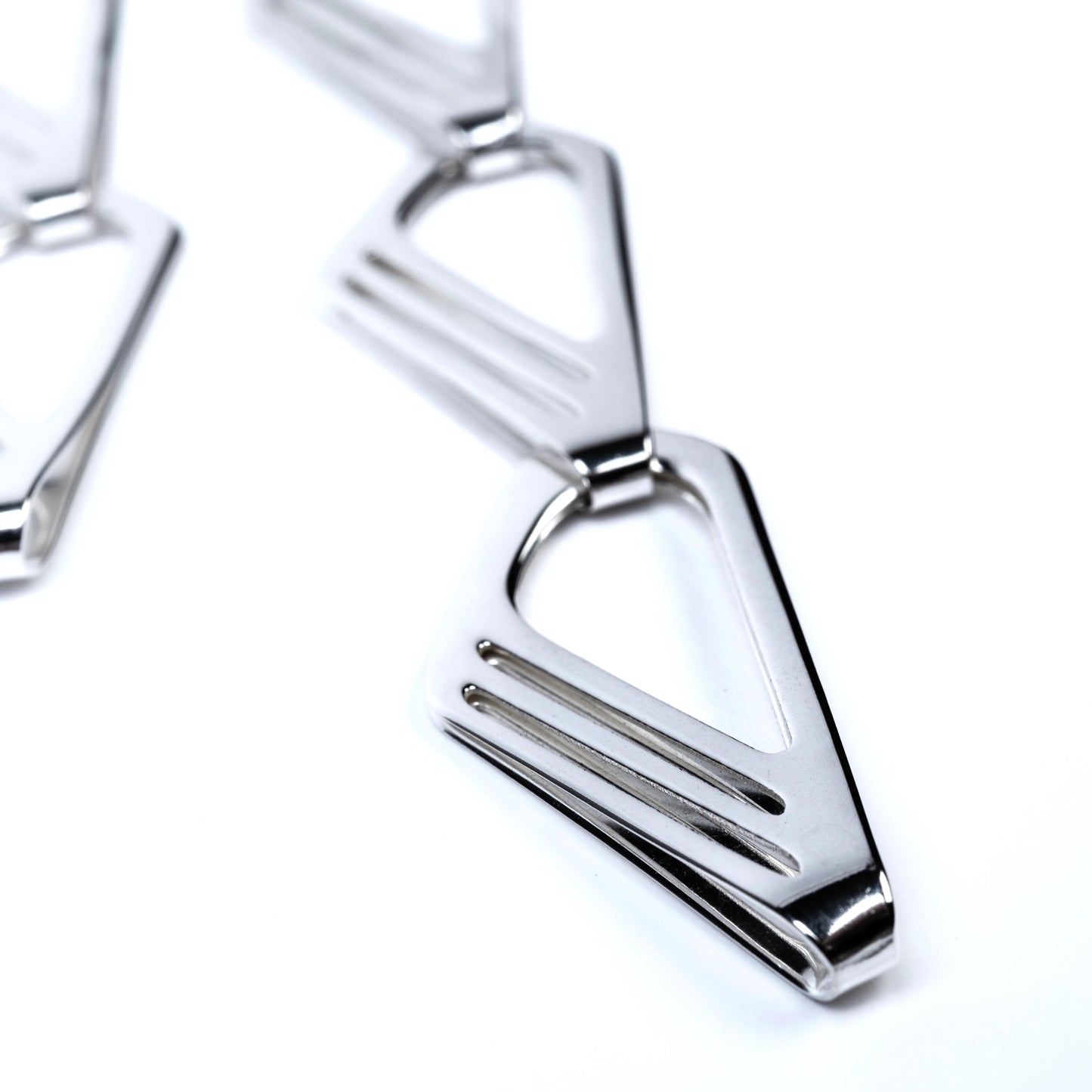 Close-up of sterling silver long drop earrings with geometric cut outs on a white background