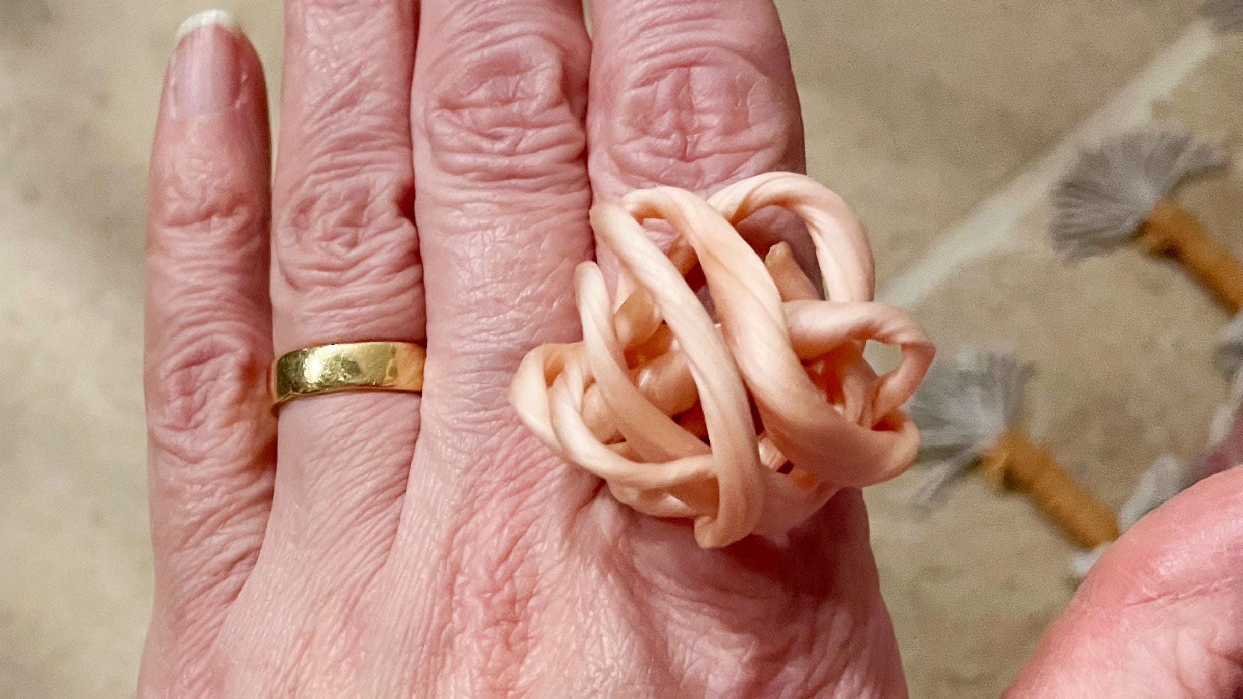 Loops of wax arranged to make a ring sitting on a hand.
