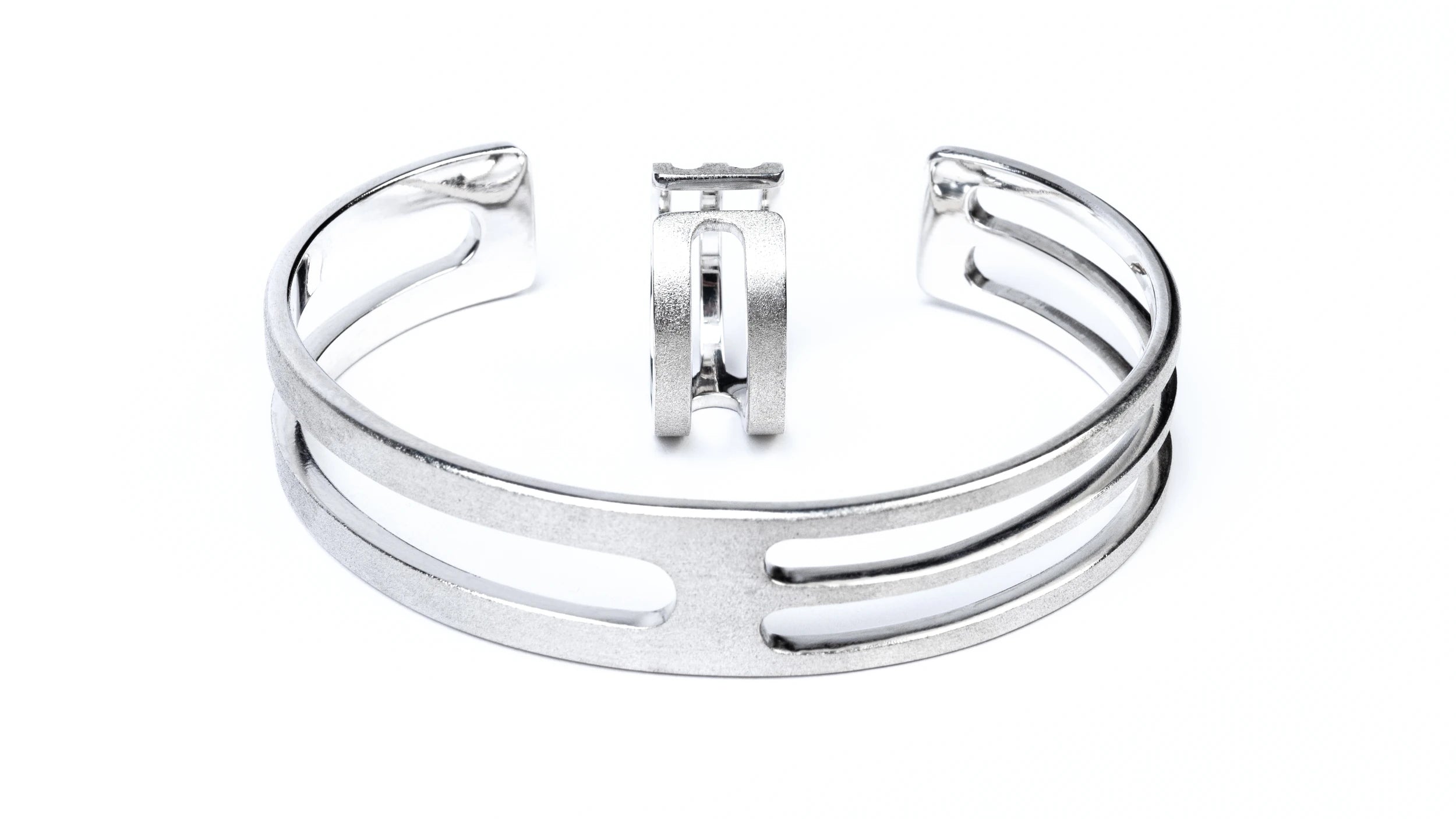 Chunky geometric silver cuff and matching ring with a frosted exterior finish and smooth highly polished interior, against a white background.