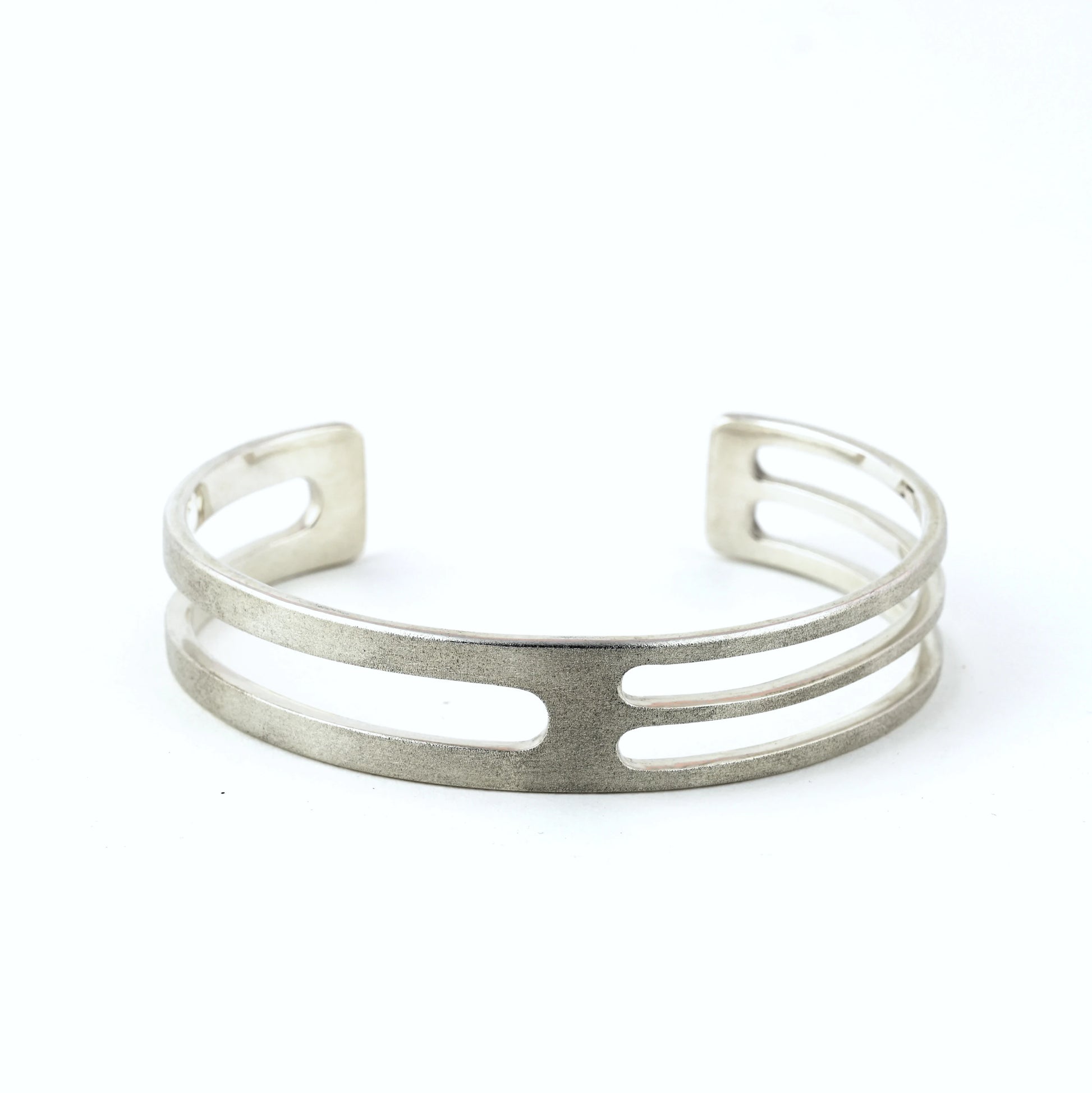 Mens silver cuff bracelet with geometric cut outs on a white background