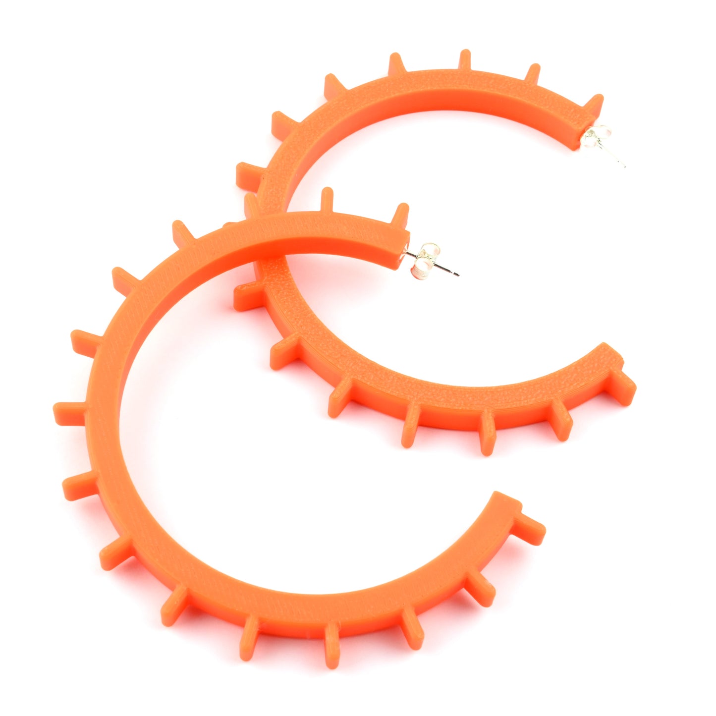 Pair of big orange cog shaped hoop earrings with silver ear posts on a white background