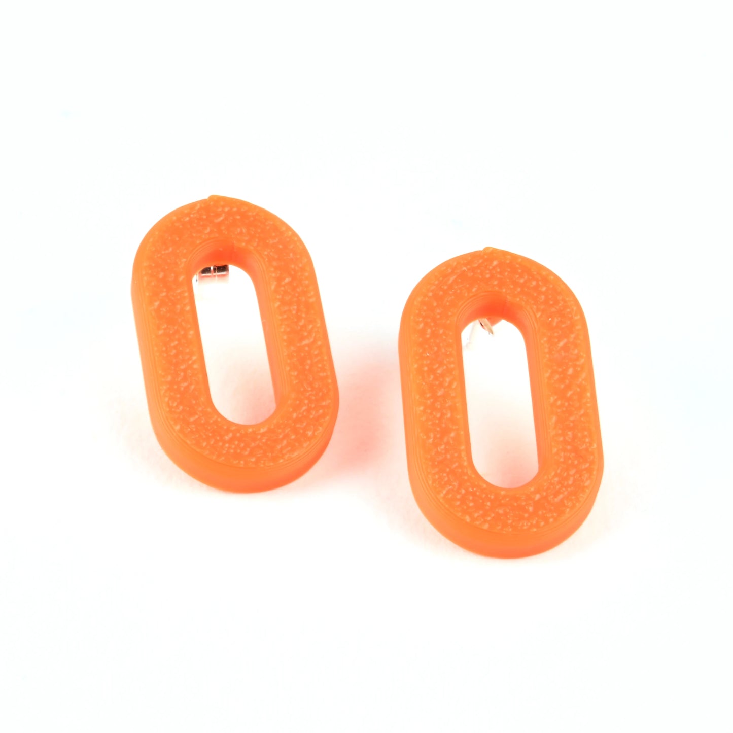 Two orange oval stud earrings with a textured surface on a white background