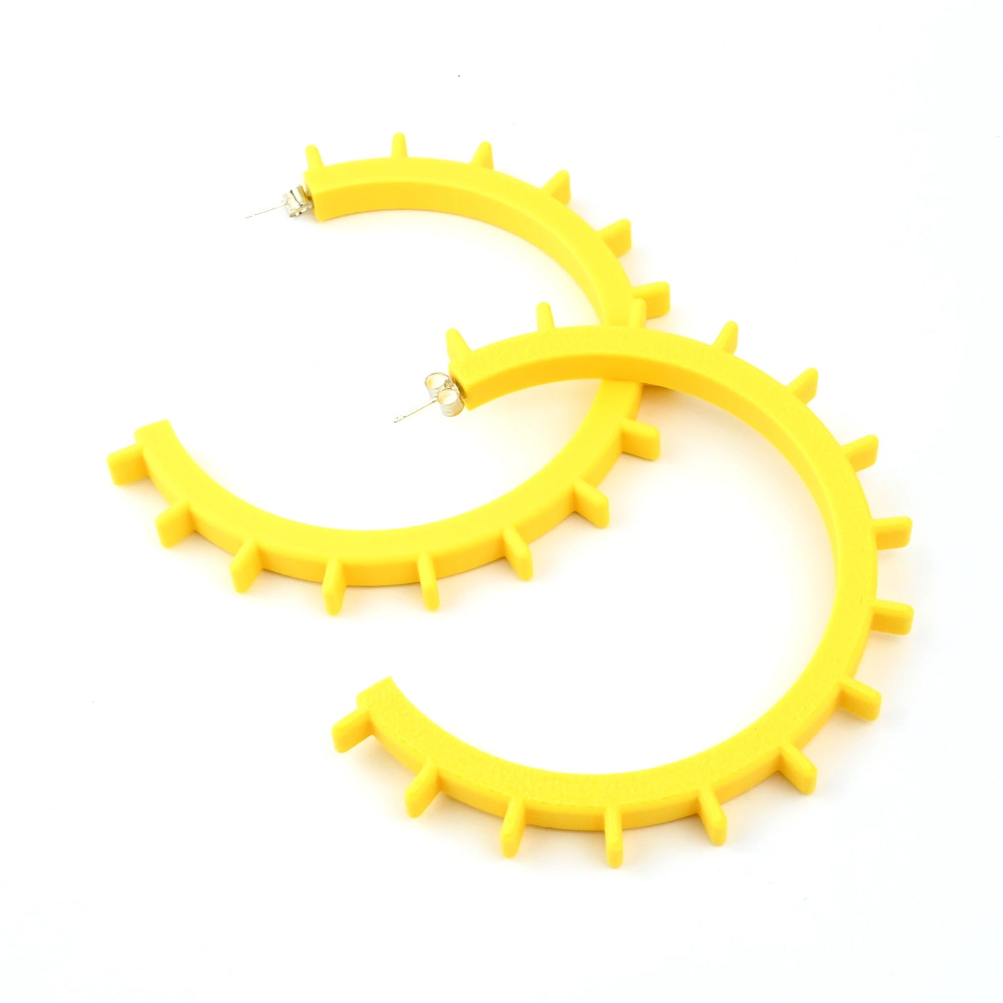 Pair of big yellow cog shaped hoop earrings with silver ear posts on a white background