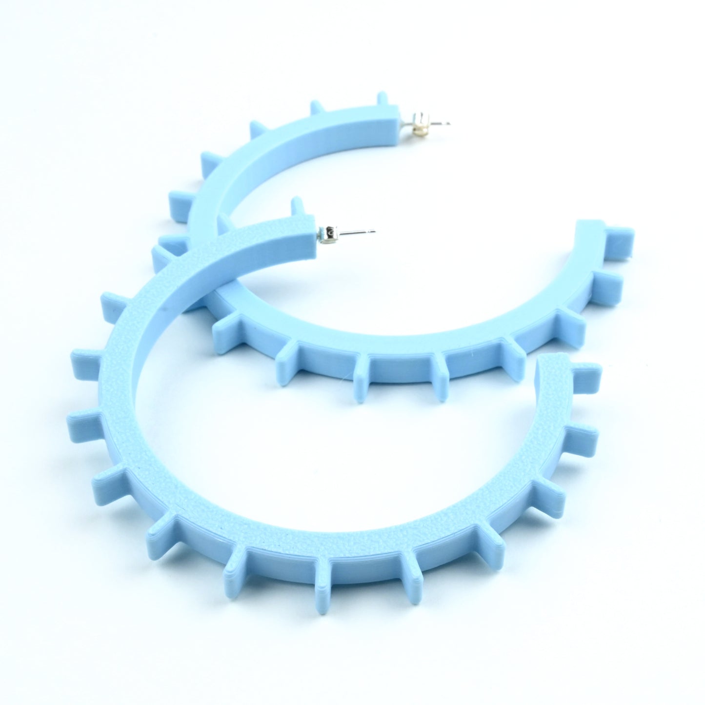 Pale blue plastic hoop earrings with silver ear posts and silver earring scroll backs. The earrings have ridges along the front edge of the hoops