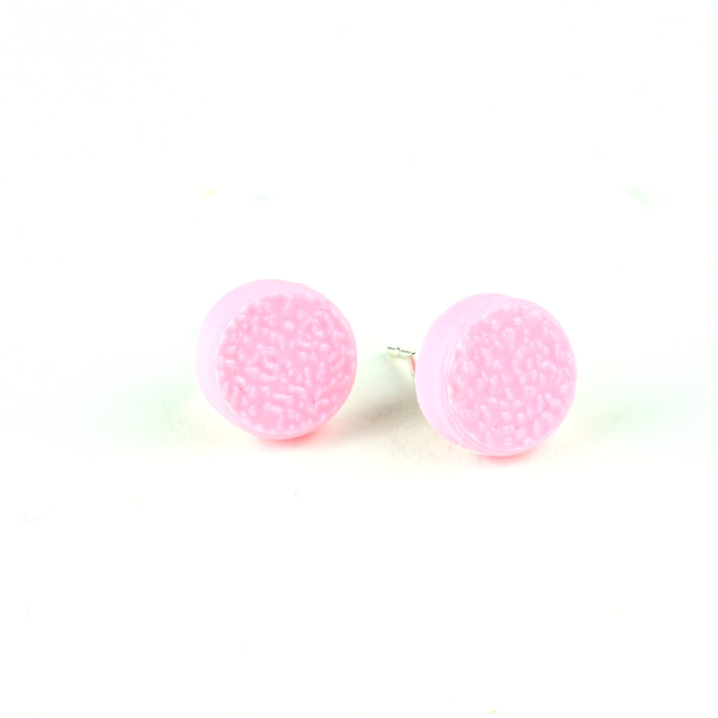 Pair of tiny pale pink textured round stud earrings on a white background