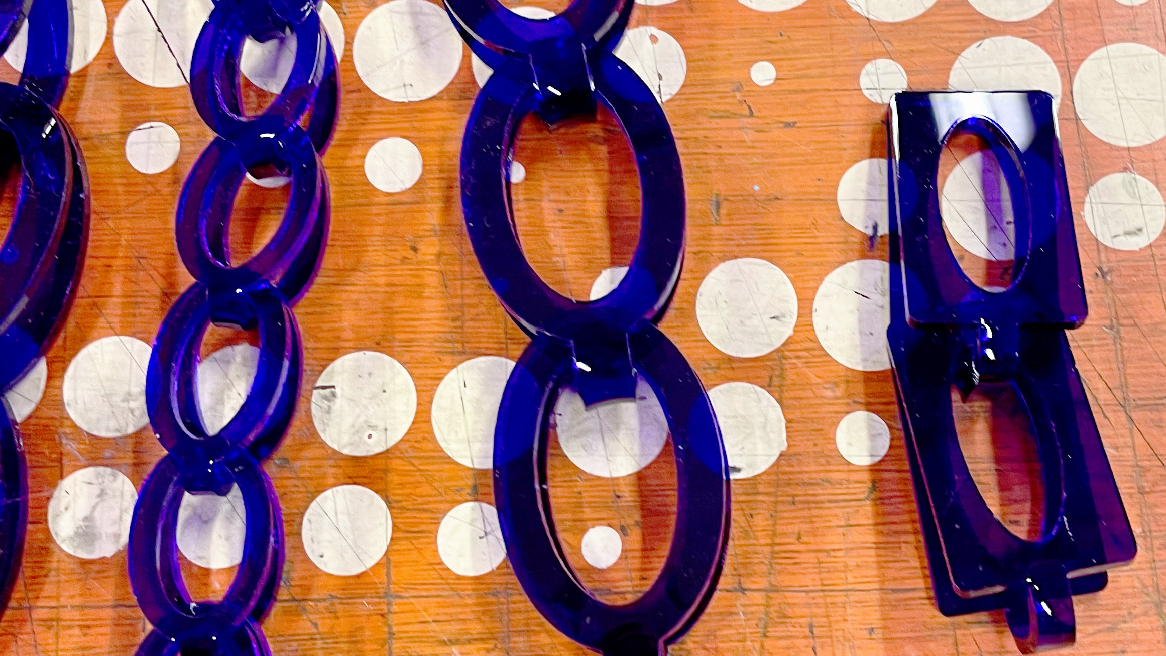 Several loop-in-loop chains made using purple acrylic sheet.  The link shapes vary in size and are either oval or rectangular.  The chains are all large in size.