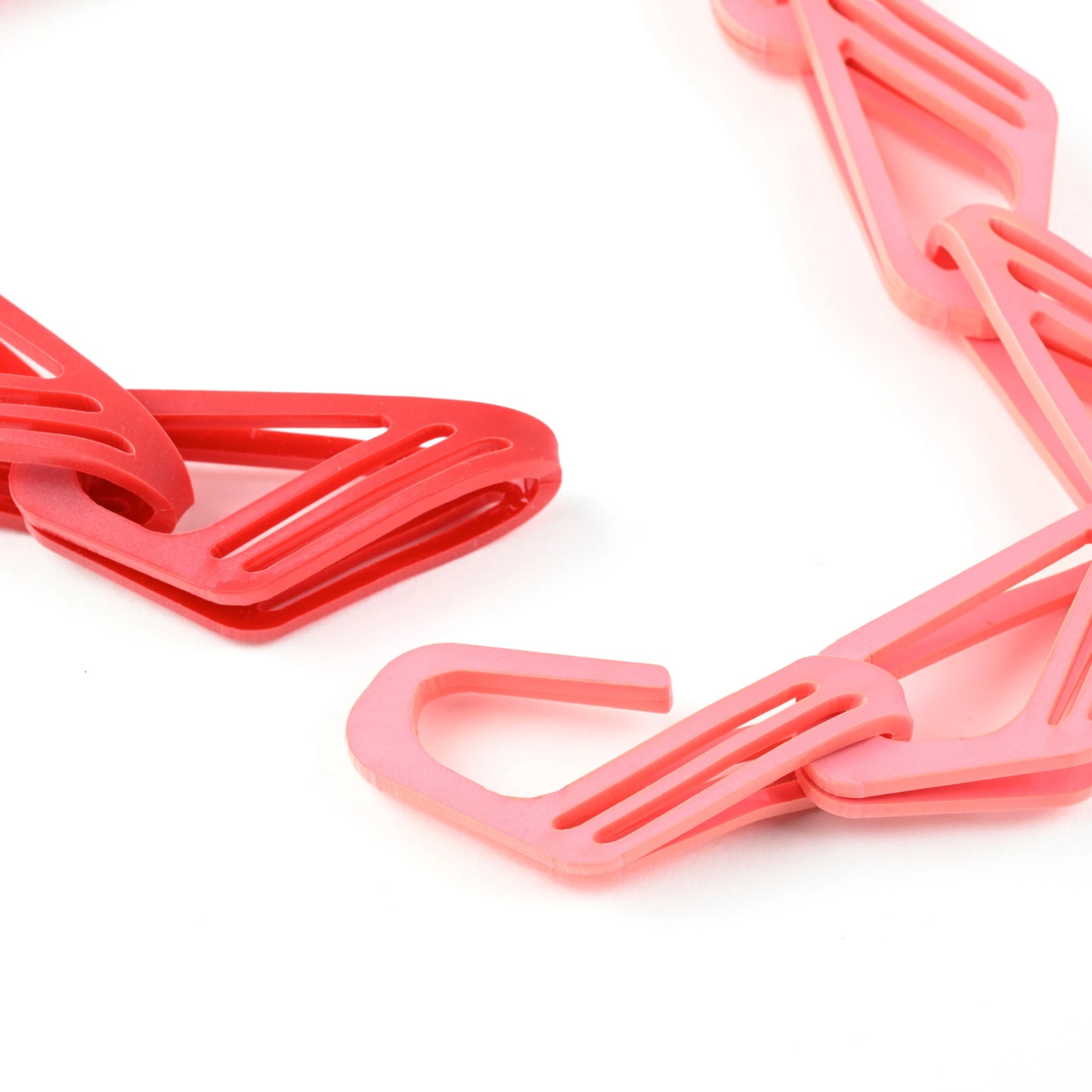 Close-up of The Halite Bold Acrylic Chain with interlocking pink & red links on a white background.