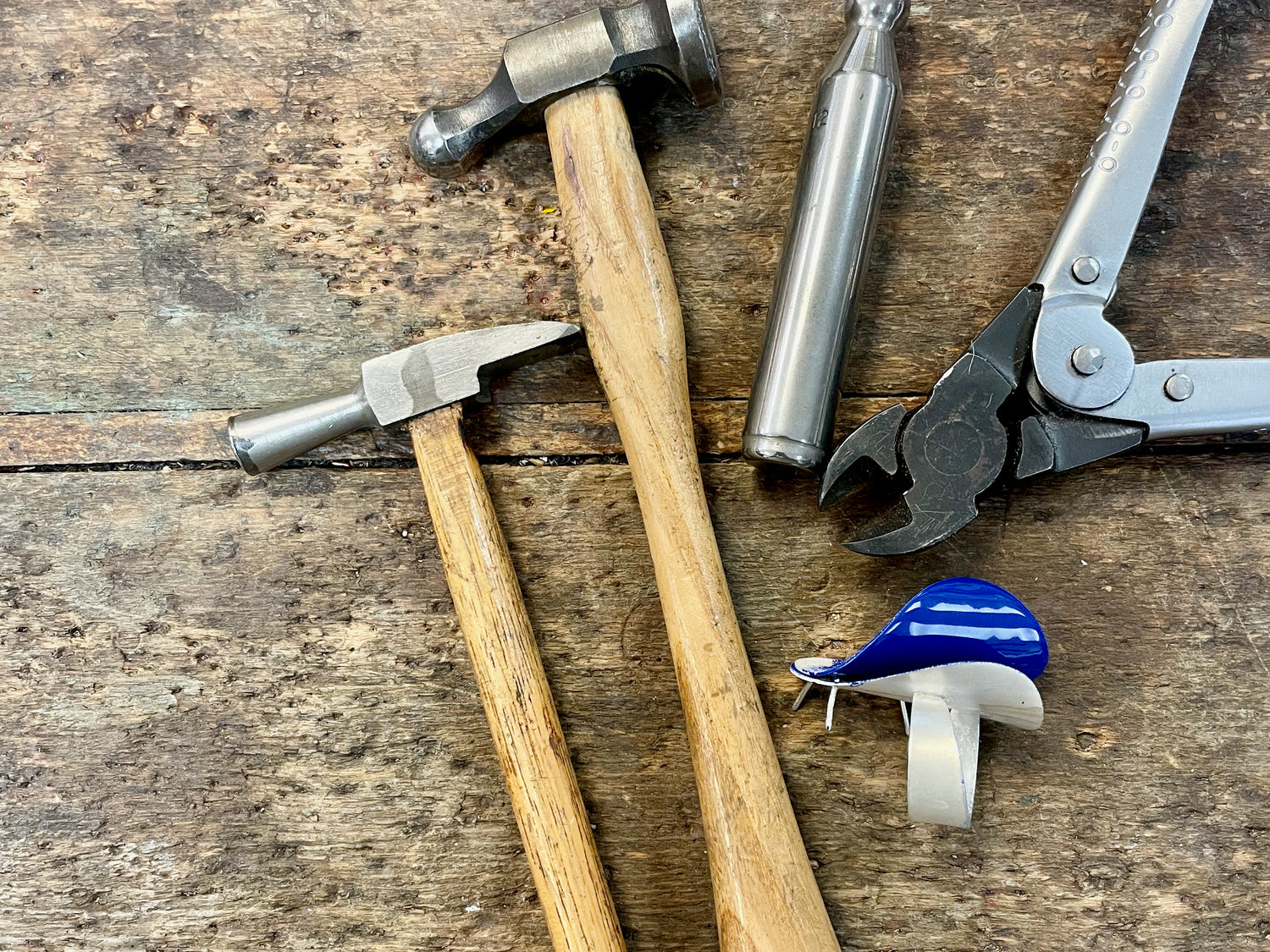 Hammers, metal snips and an unfinished ring on a workbench.