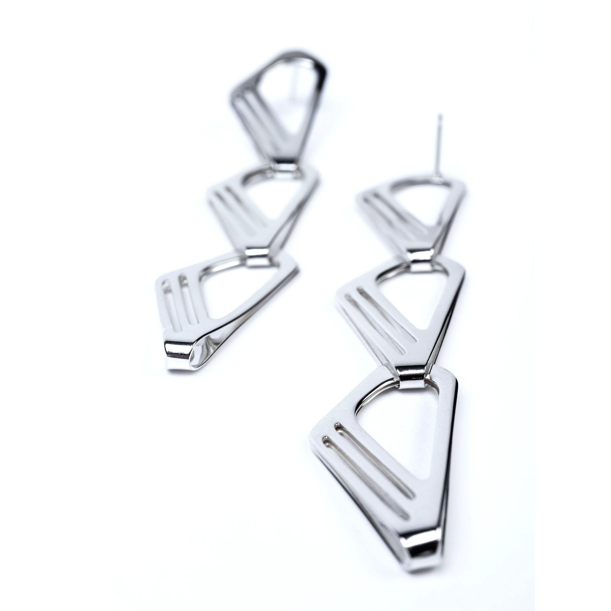 Pair of polished silver geometric earrings with cut out detail on a white background