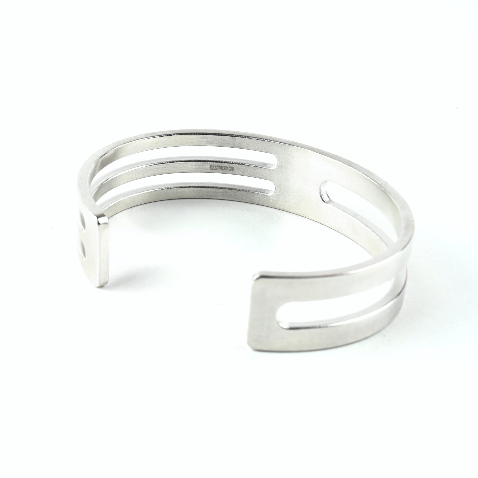Sterling silver cuff bracelet with geometric design and hallmark on a white background
