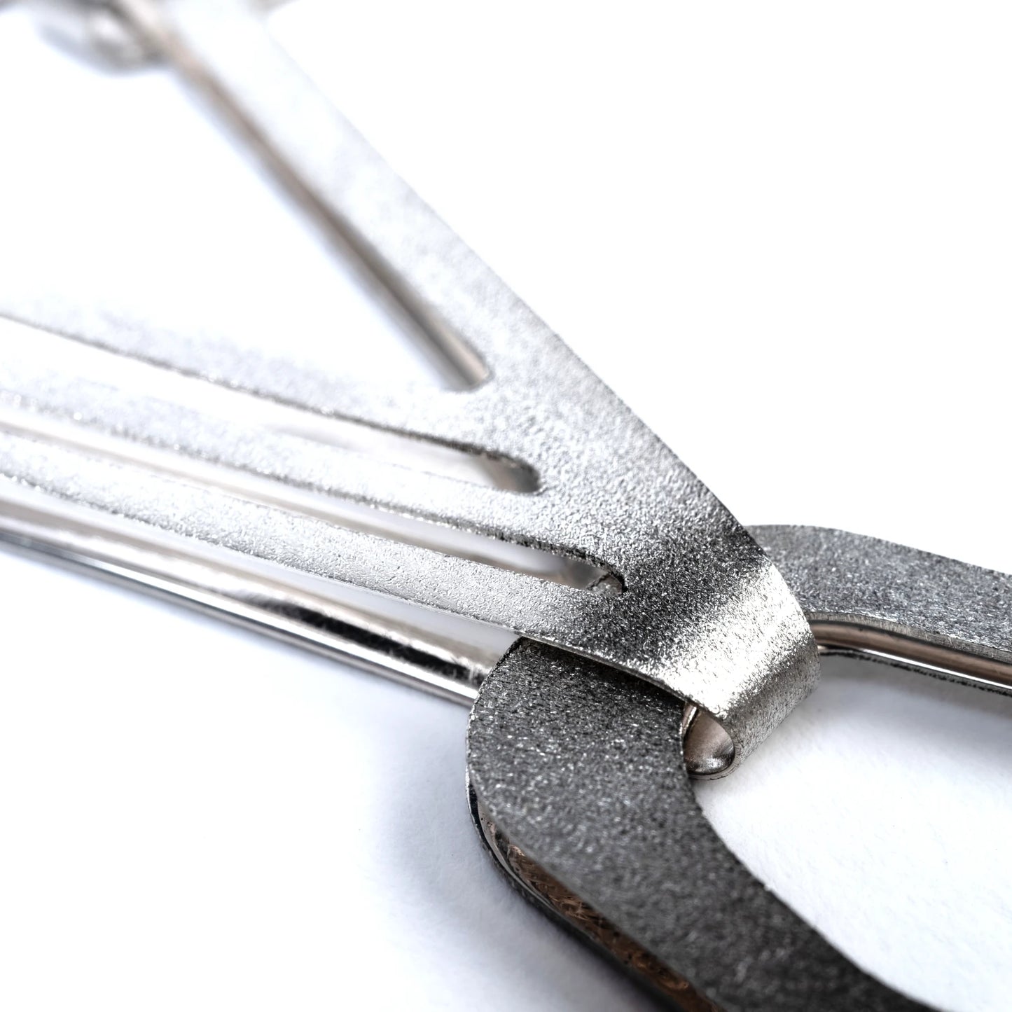 Close up of silver chain link with with textured design on a white background