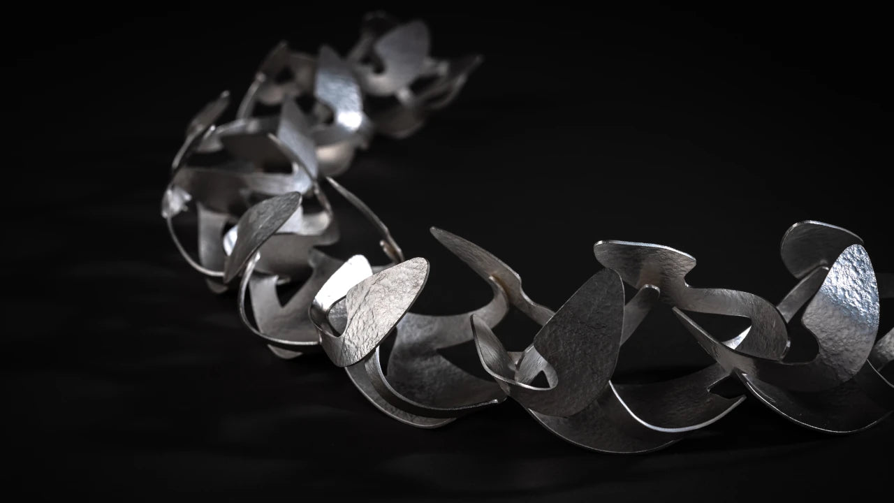 Dramatic statement silver collar made up of large organic shapes interlinked, on a black background